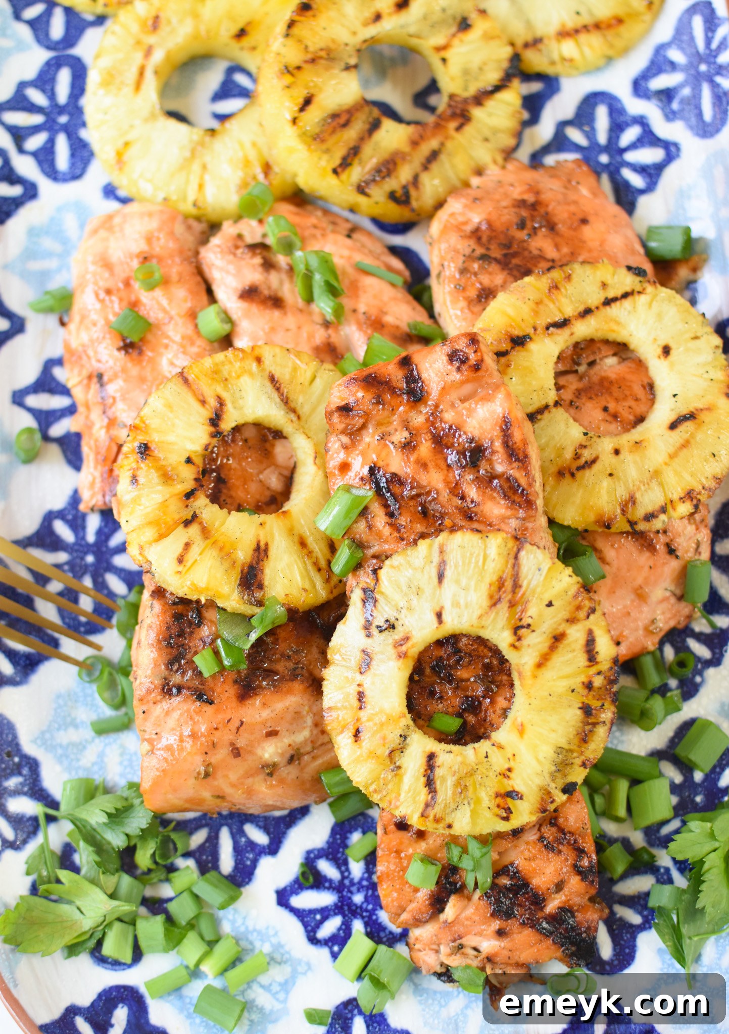 Hawaiian Grilled Salmon on a blue platter, garnished with fresh green onions and juicy grilled pineapple slices.