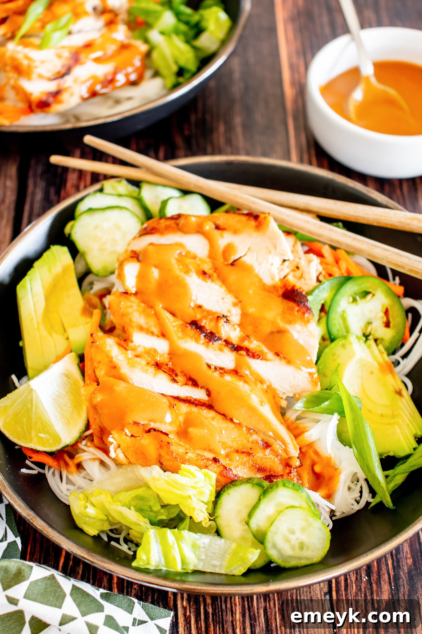 Thai Chicken Noodle Salad garnished with fresh lime wedges, ready to be served.