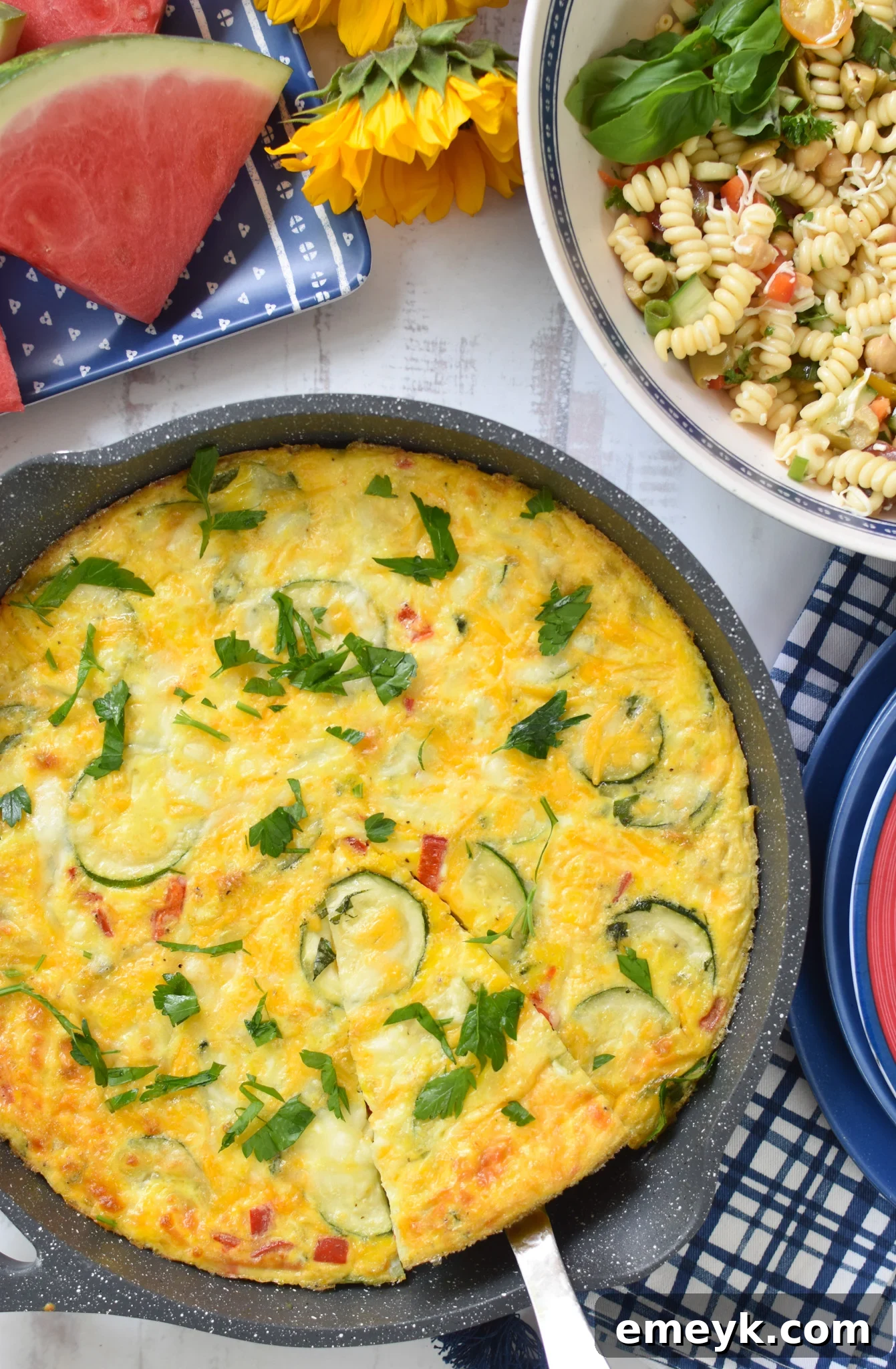 Zucchini Frittata Recipe in a skillet with blue napkins. A perfect summer egg dish.