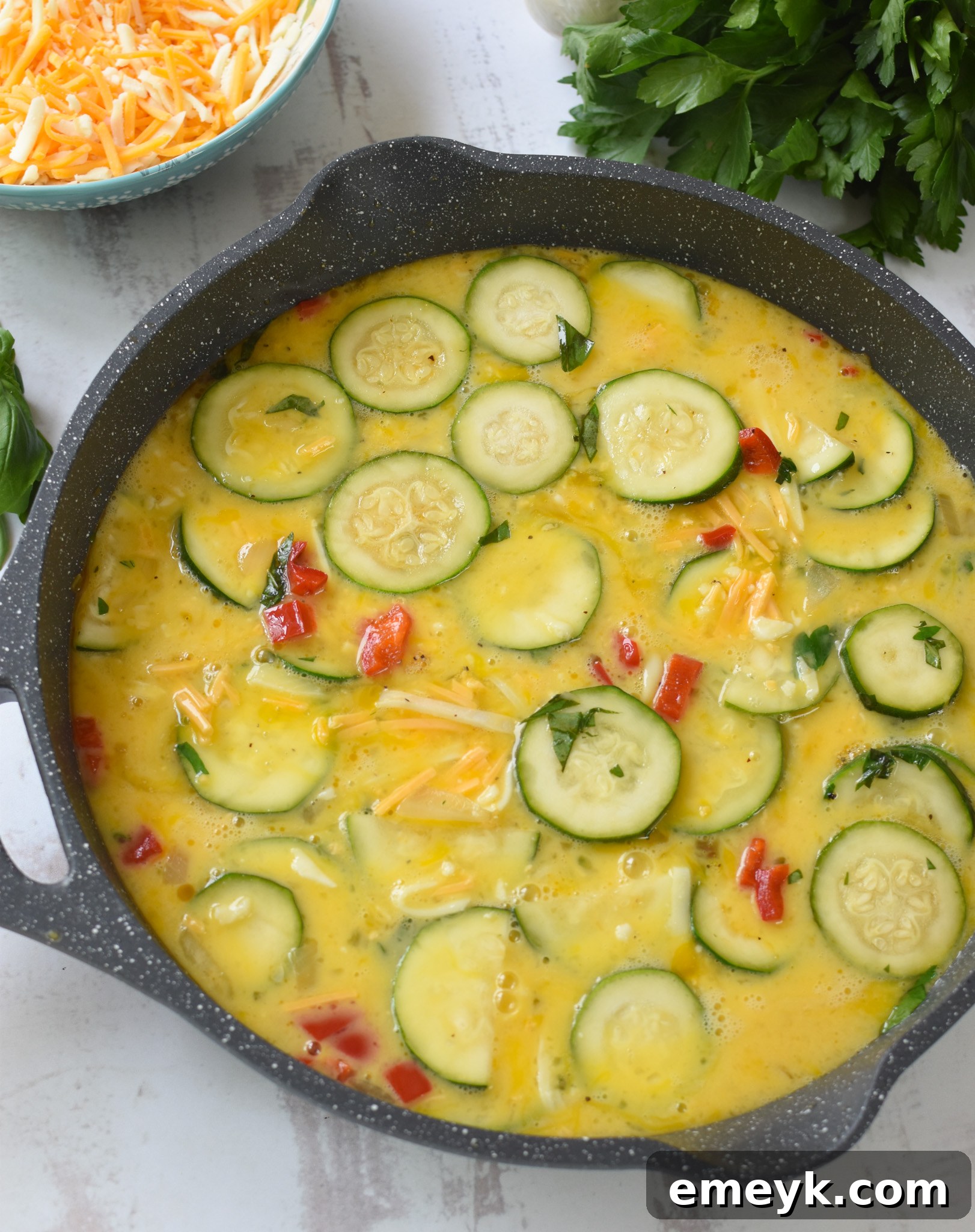 Zucchini Frittata Recipe with eggs and vegetables combined in a skillet.