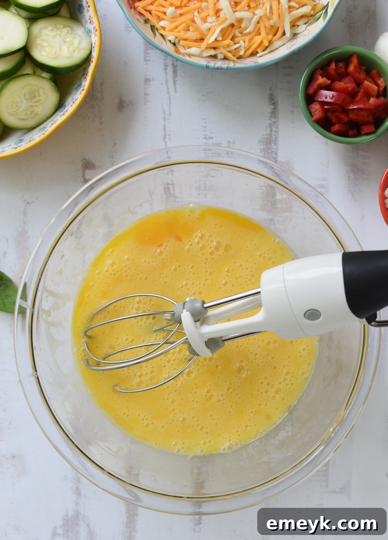 Zucchini Frittata Recipe with whisk, showing eggs and milk being mixed.
