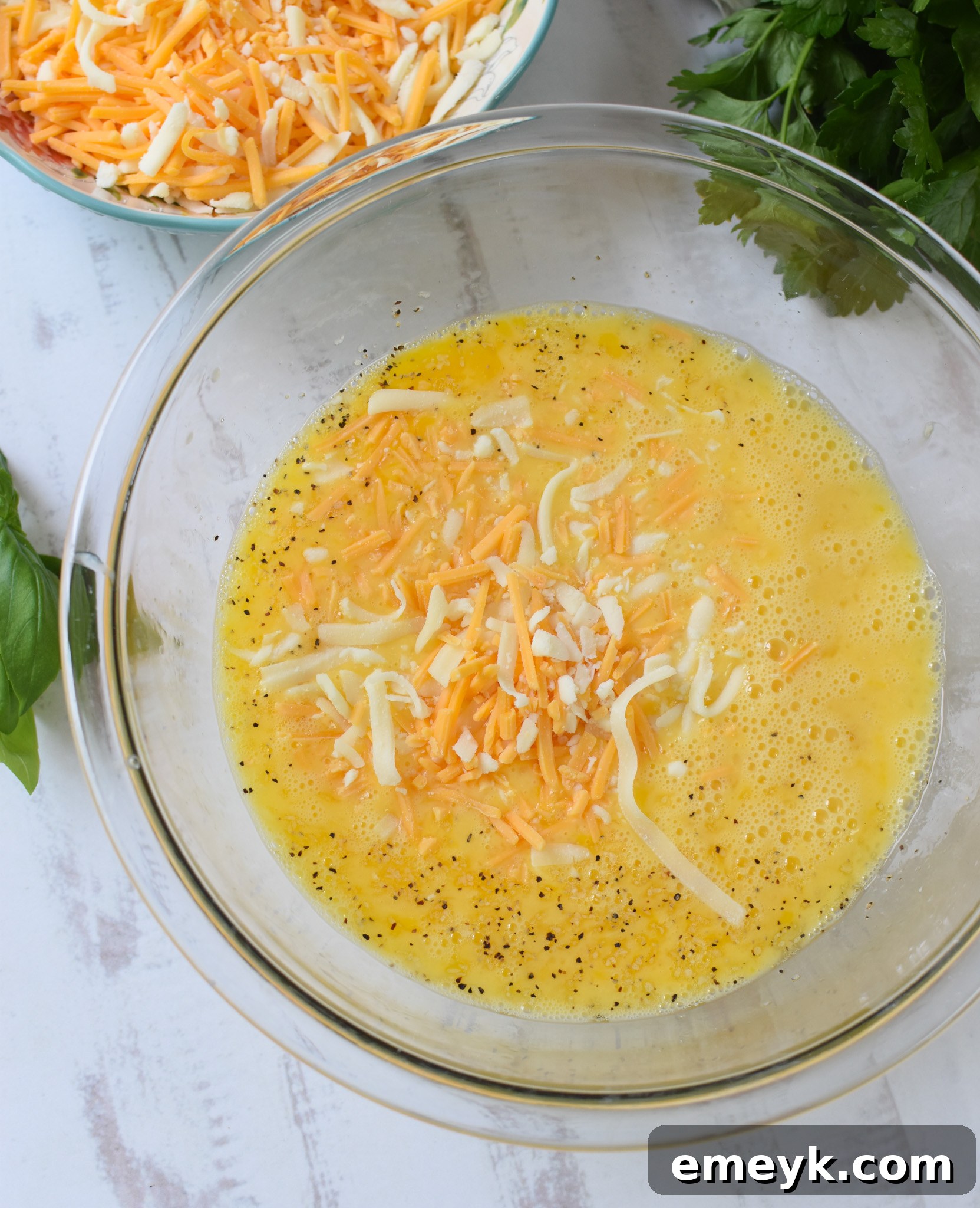 Zucchini Frittata Recipe with cheese and eggs in bowl, after mixing.