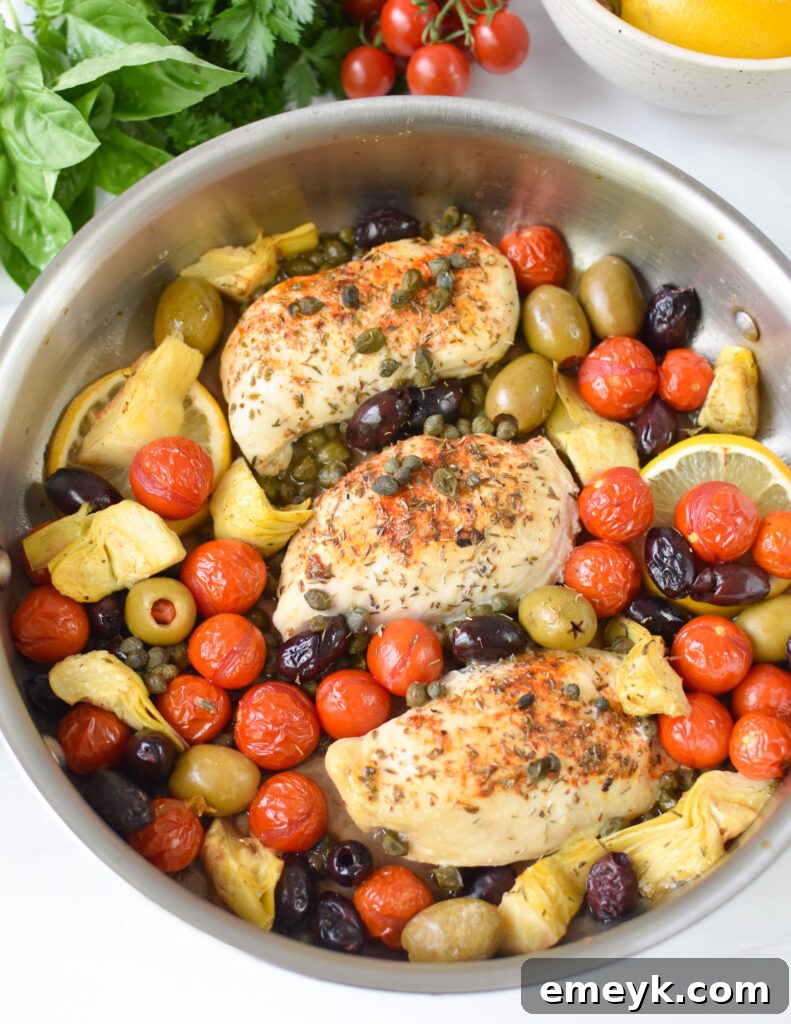 Close-up of perfectly seared chicken breasts in a skillet, ready for the oven with other ingredients.