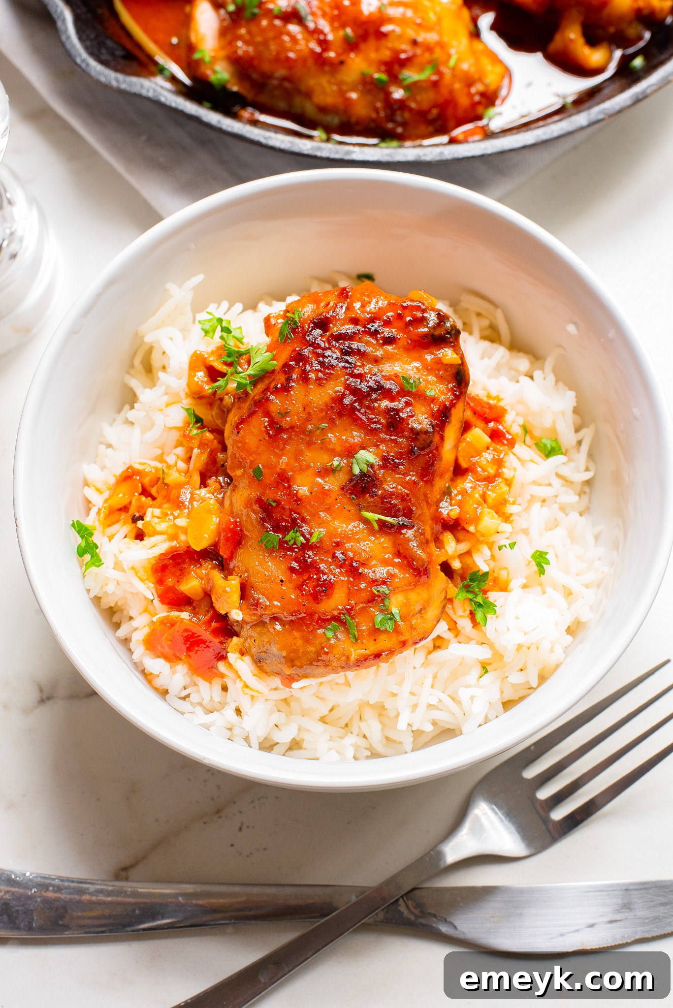 Harissa Chicken Recipe in a white bowl, garnished with fresh herbs.