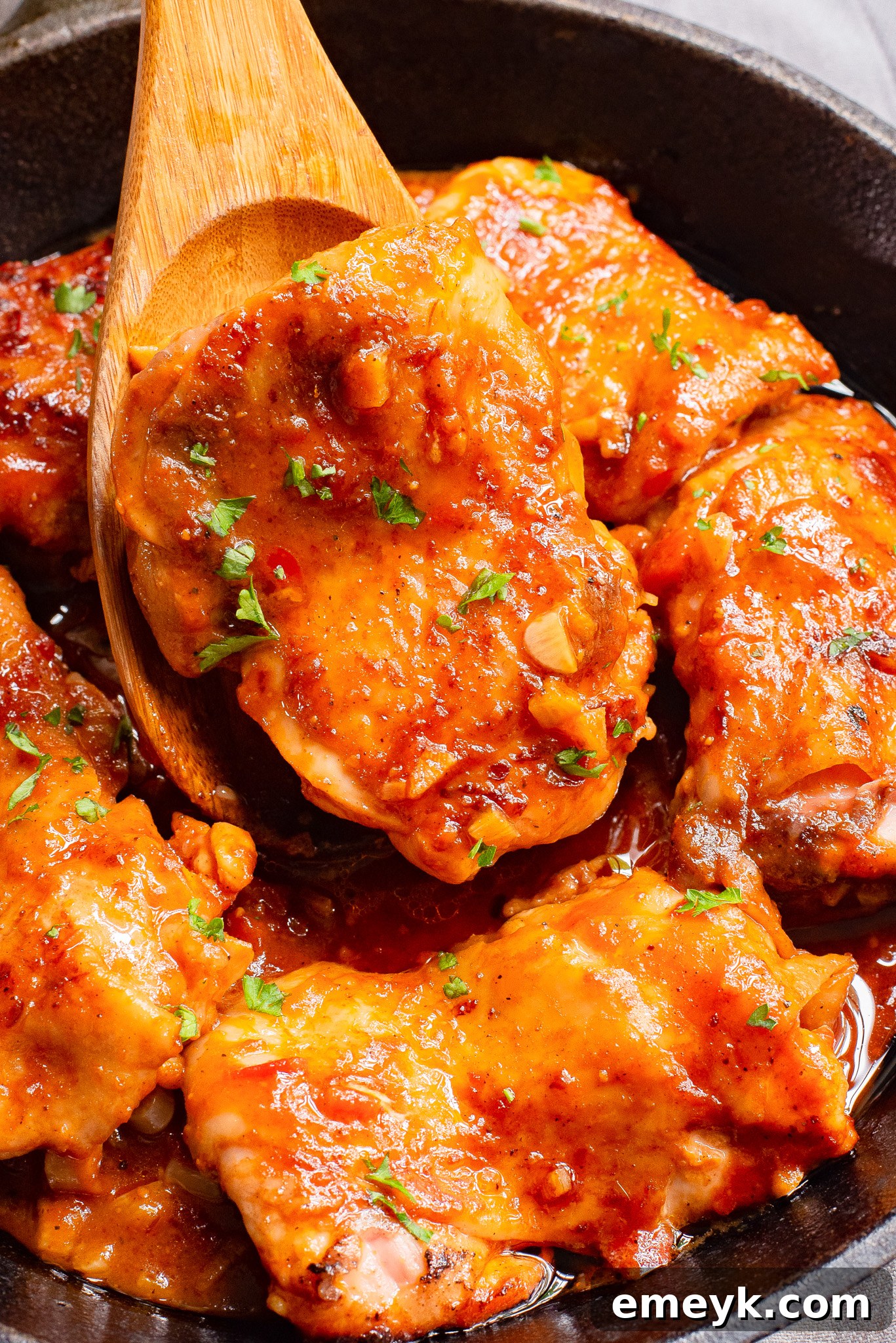 Harissa Chicken Recipe served with a spoon and fresh herbs.