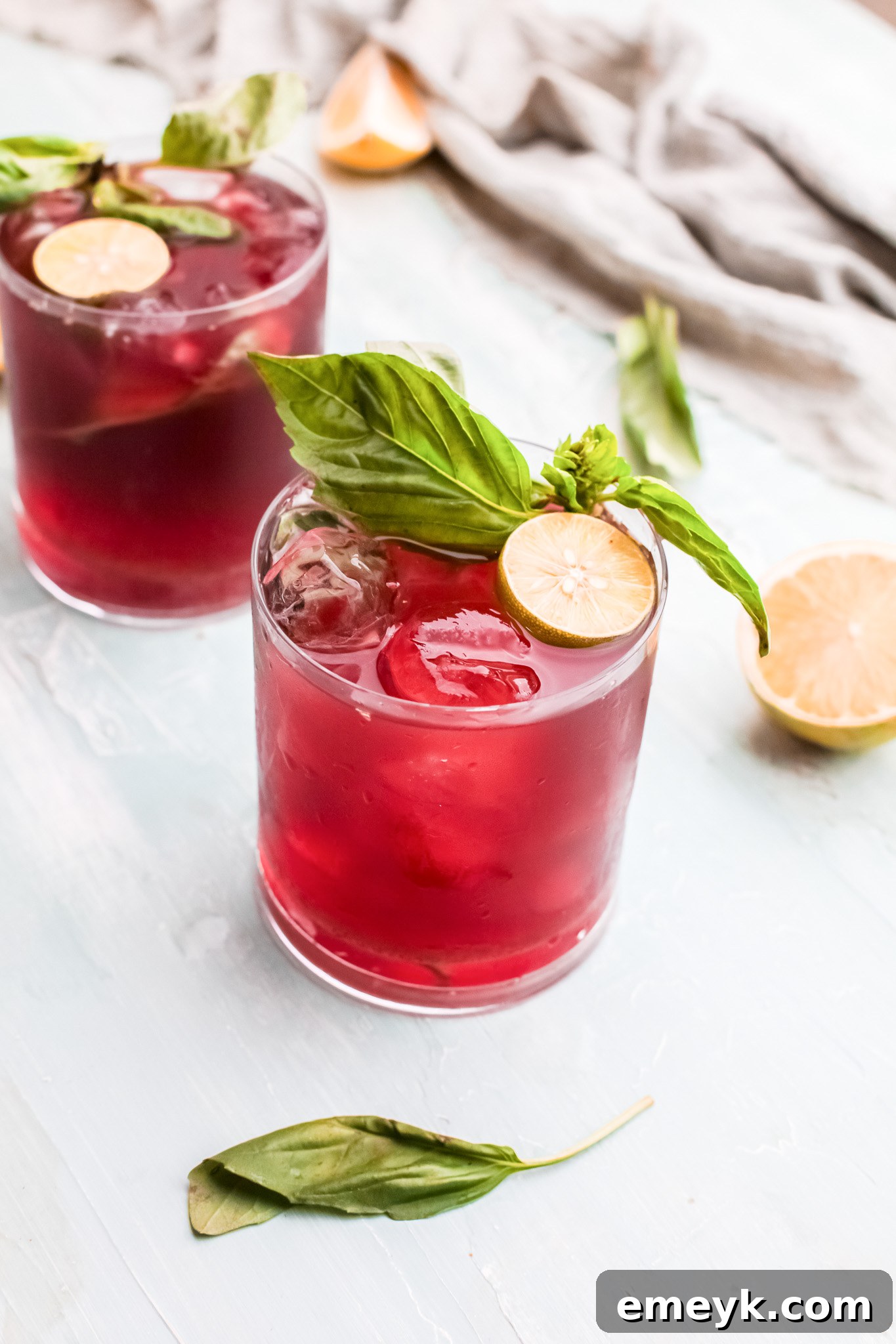 A refreshing glass of Vodka Cherry Limeade garnished with fresh basil, perfect for summer.
