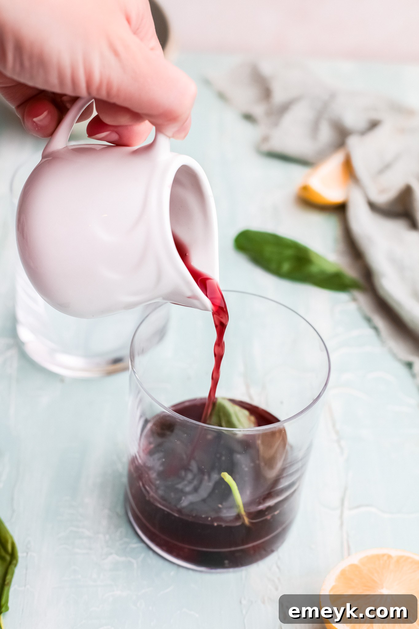 Pouring cherry juice into a glass with muddled ingredients for Vodka Cherry Limeade.