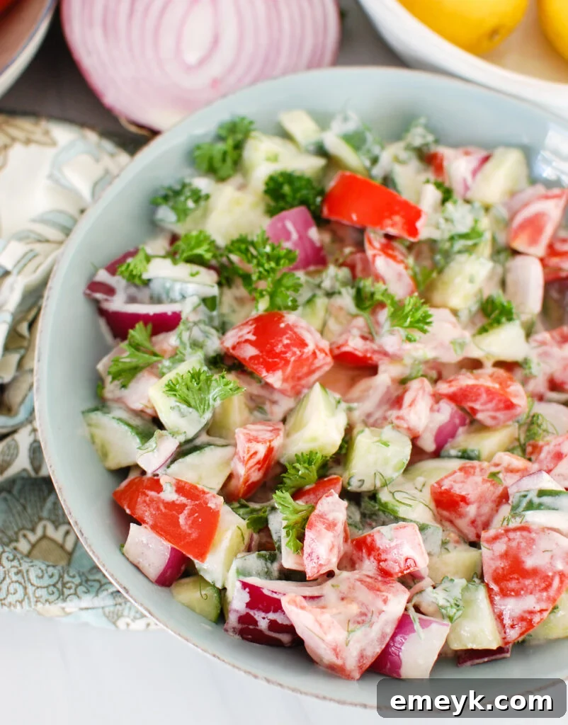 Tomato Cucumber Salad with Yogurt Dressing in teal bowl, showcasing fresh ingredients and vibrant colors.