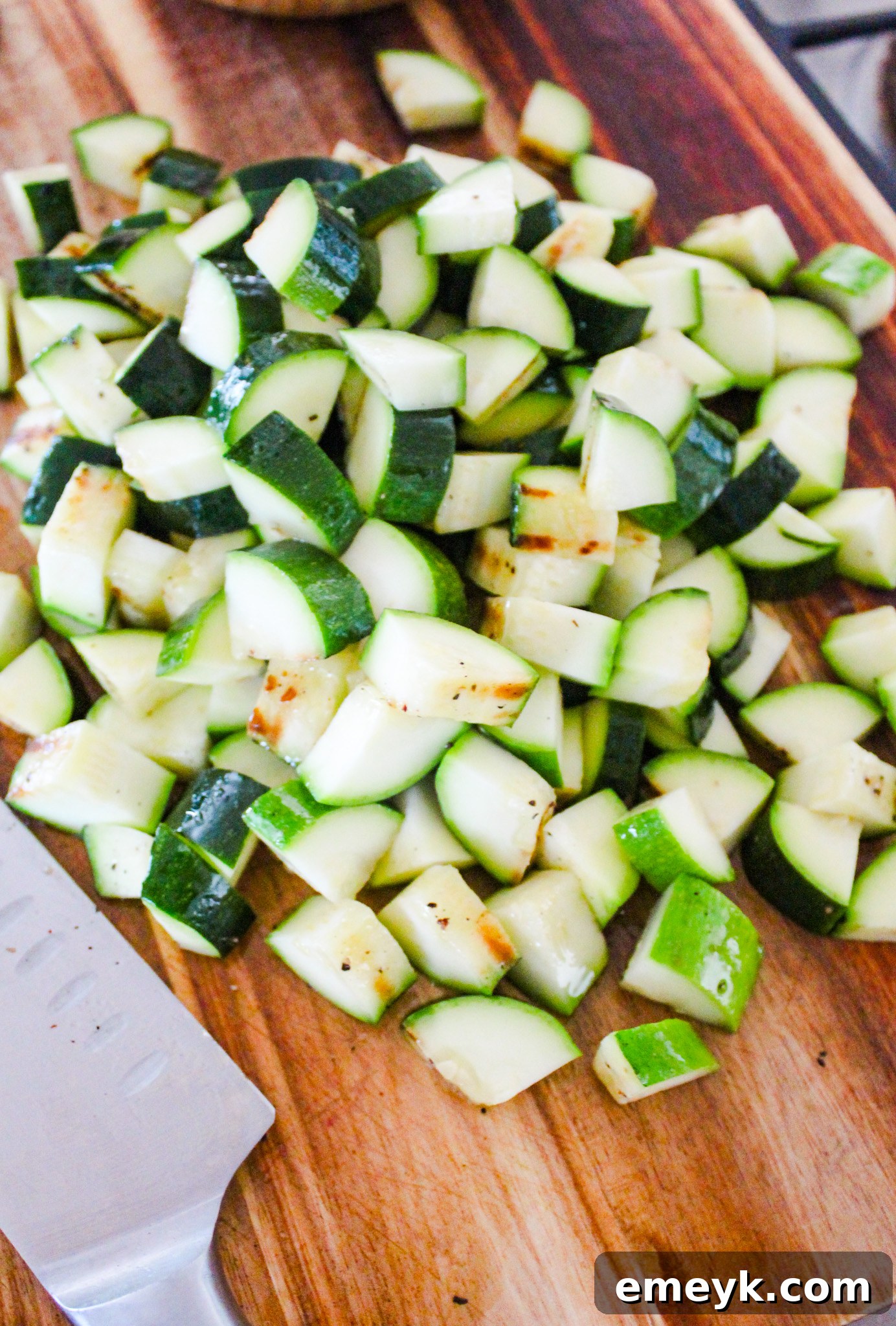 Chopped grilled zucchini and corn on a wooden cutting board, ready for taco assembly.