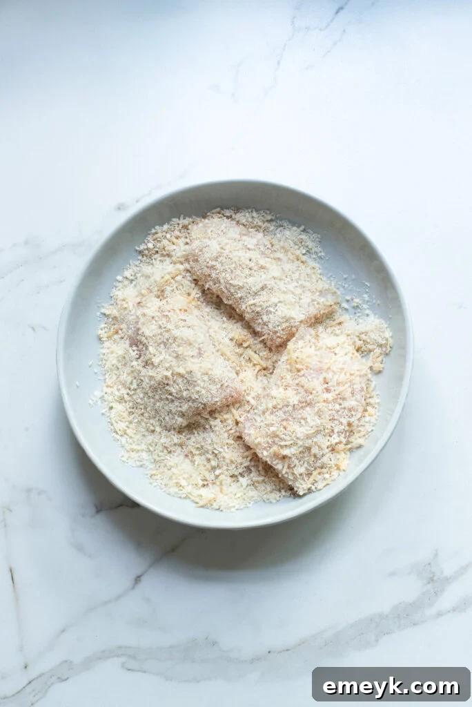 Fish fillet being coated in breadcrumbs mixture.