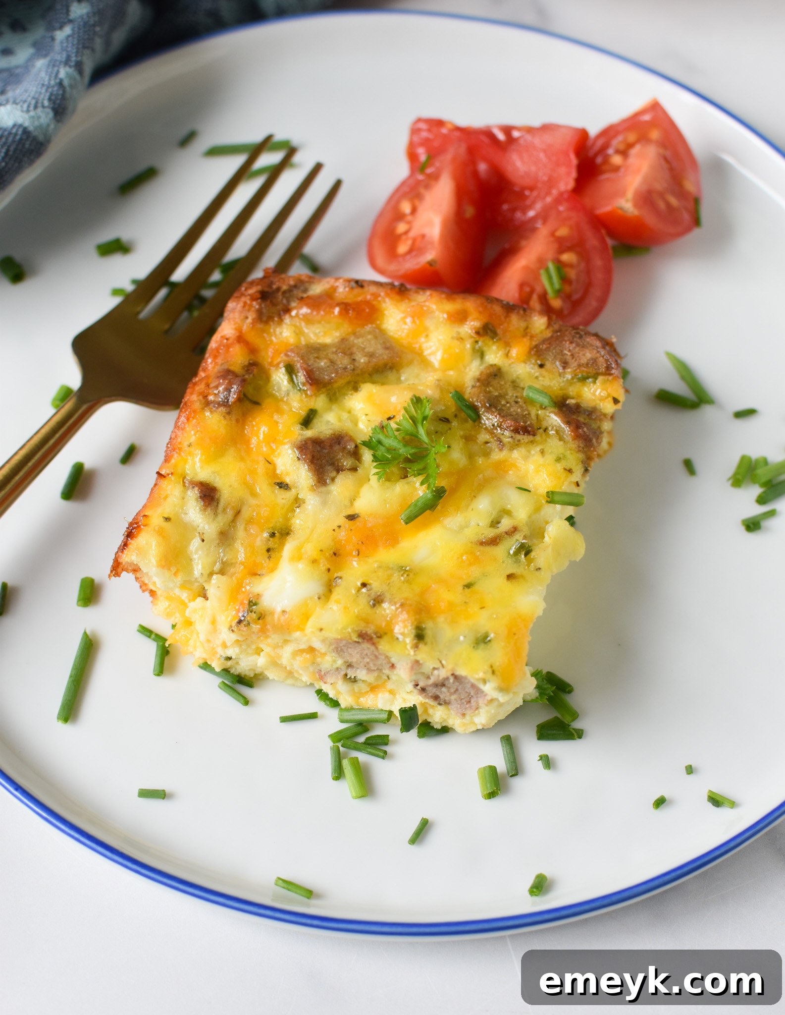 A serving of Cheese and Sausage Baked Eggs, garnished and ready to enjoy on a white plate.