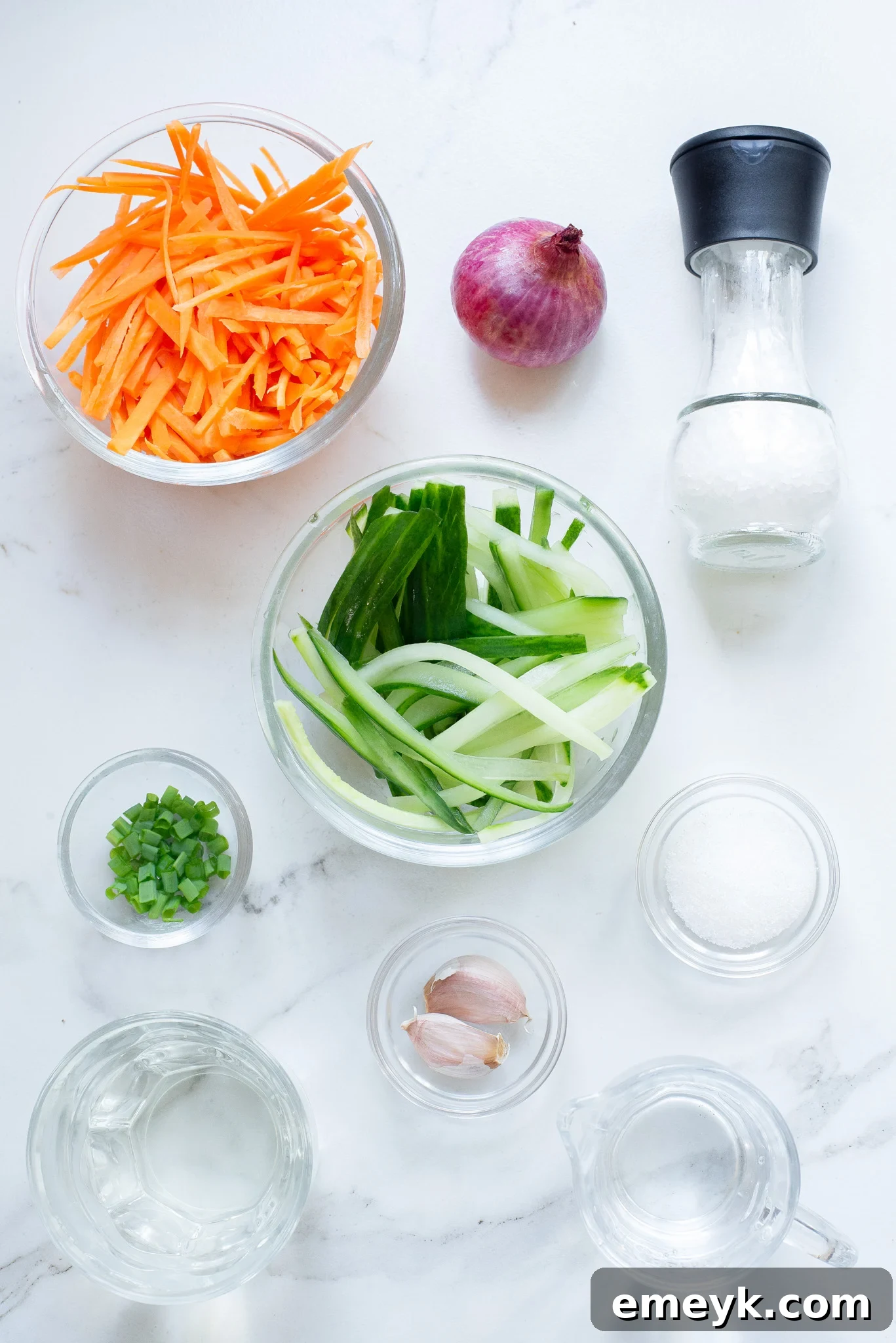 A collection of ingredients for Quick Pickled Vegetables, including carrots, cucumber, red onion, vinegar, and various spices.