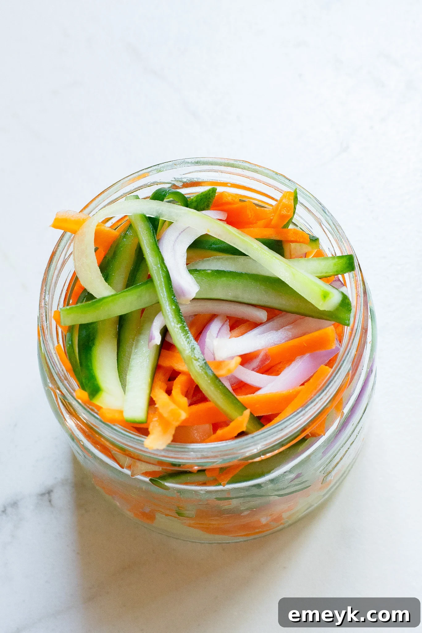 A full jar of quick pickled vegetables with a wooden lid, sitting on a wooden surface.