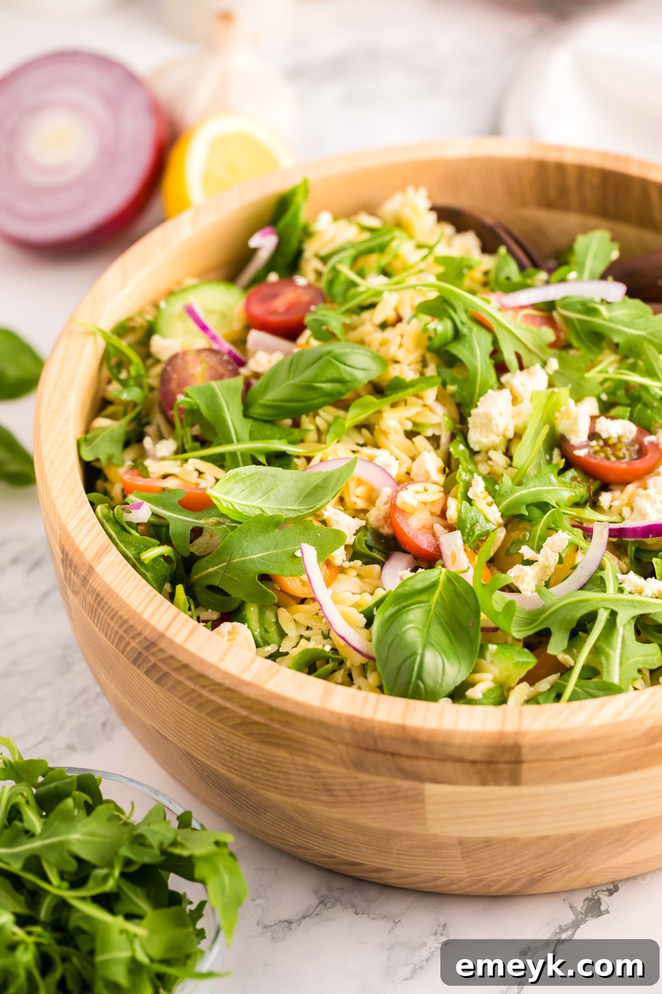 The finished Arugula Orzo Salad presented in a rustic wooden bowl.