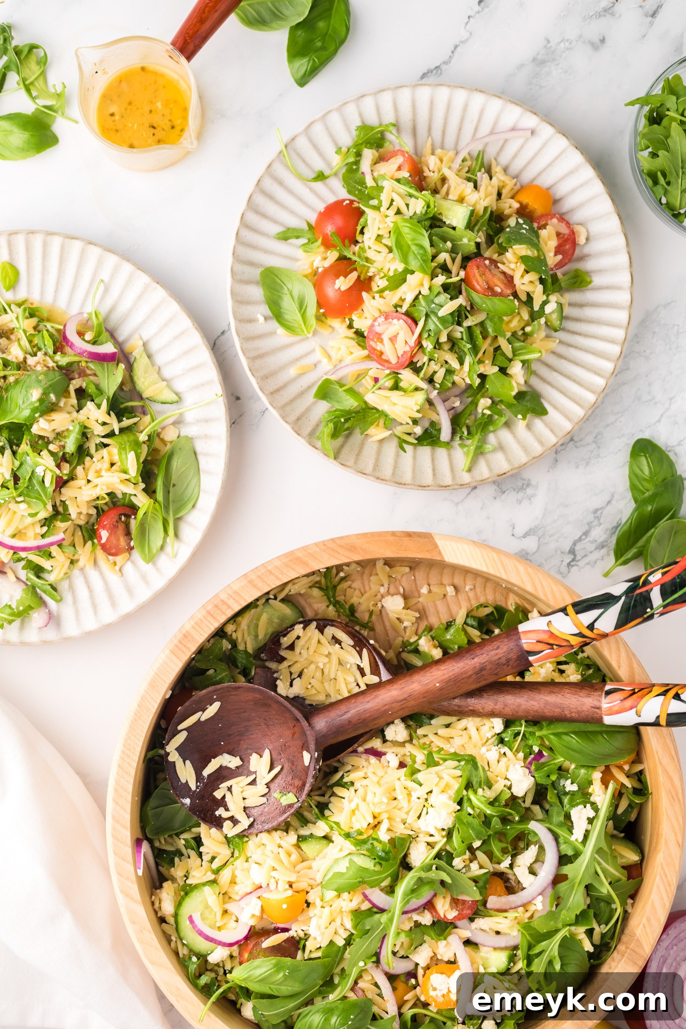 Multiple white plates filled with Arugula Orzo Salad, ready to be served.