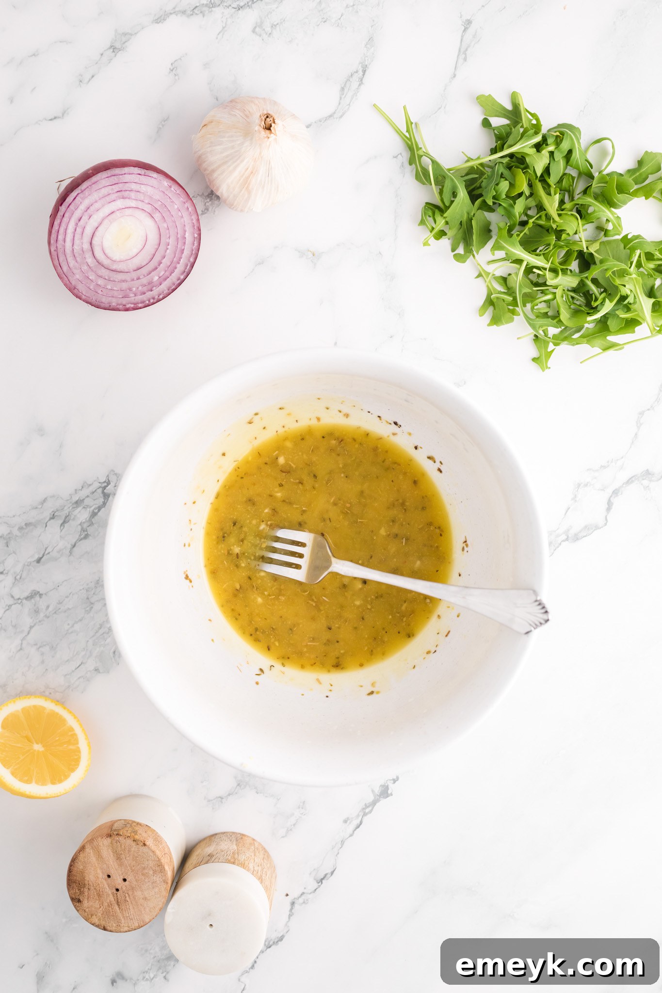 Greek salad dressing being whisked in a small bowl.