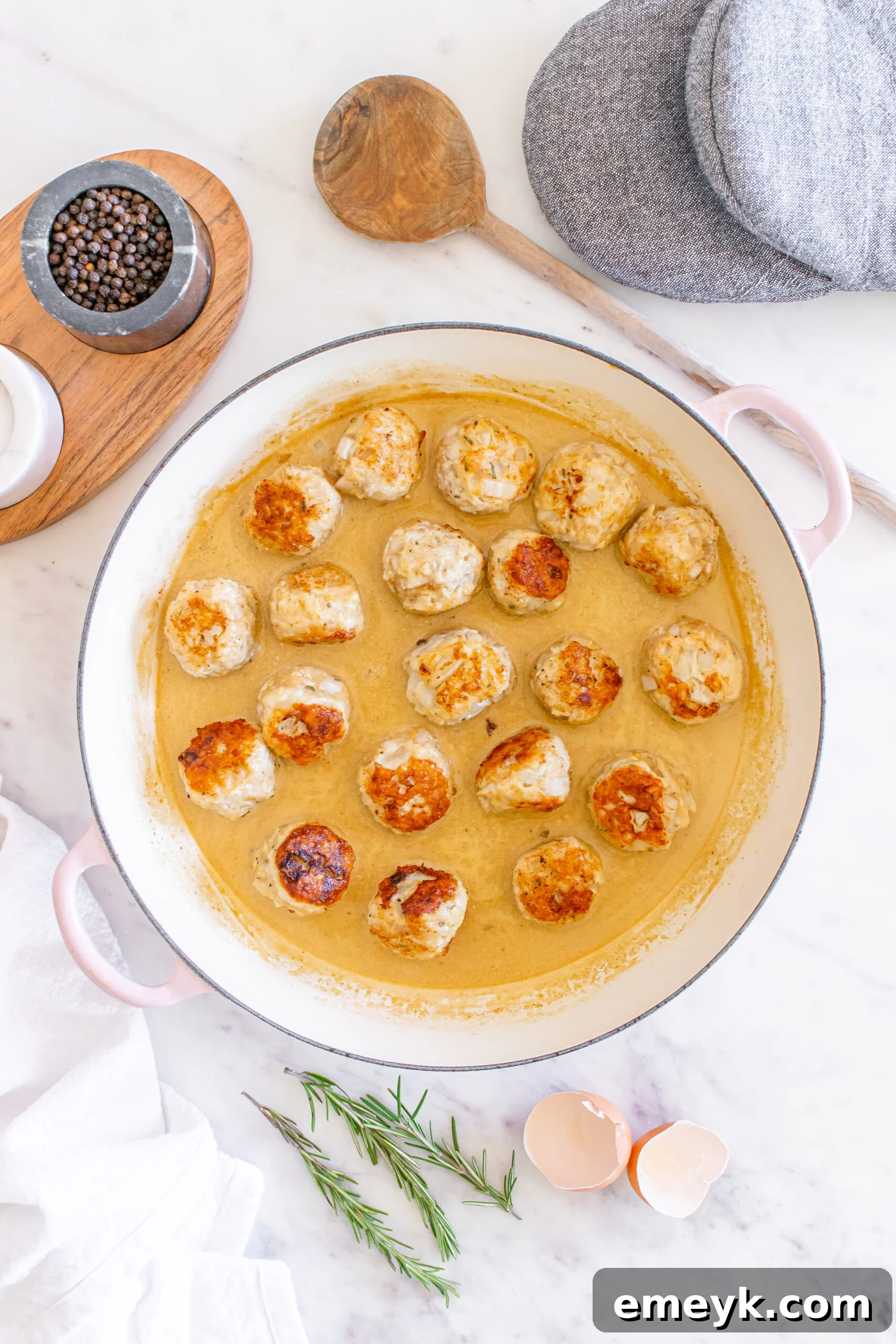 Maple Dijon Turkey Meatballs simmering in their creamy sauce in a Dutch oven, creating a comforting aroma.