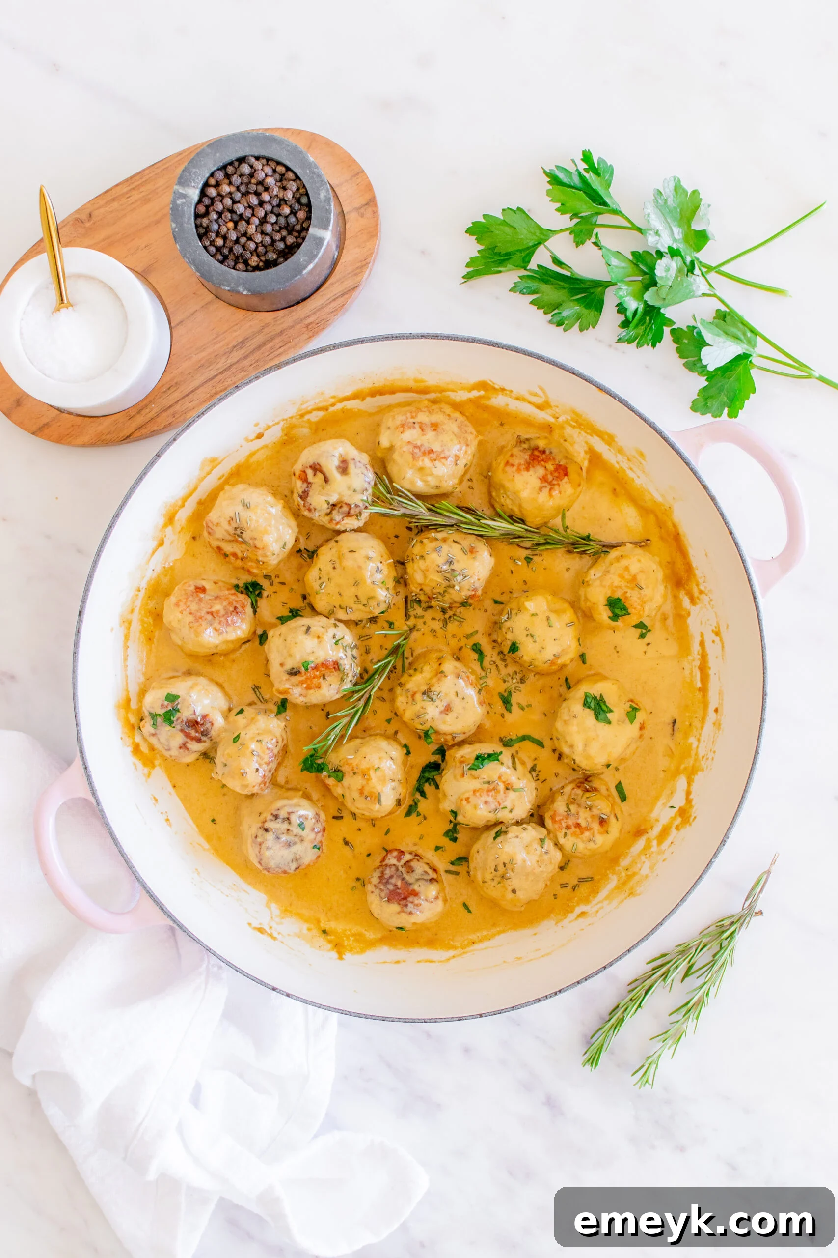 A pot of finished Maple Dijon Turkey Meatballs, perfectly coated in sauce and garnished with fresh rosemary.