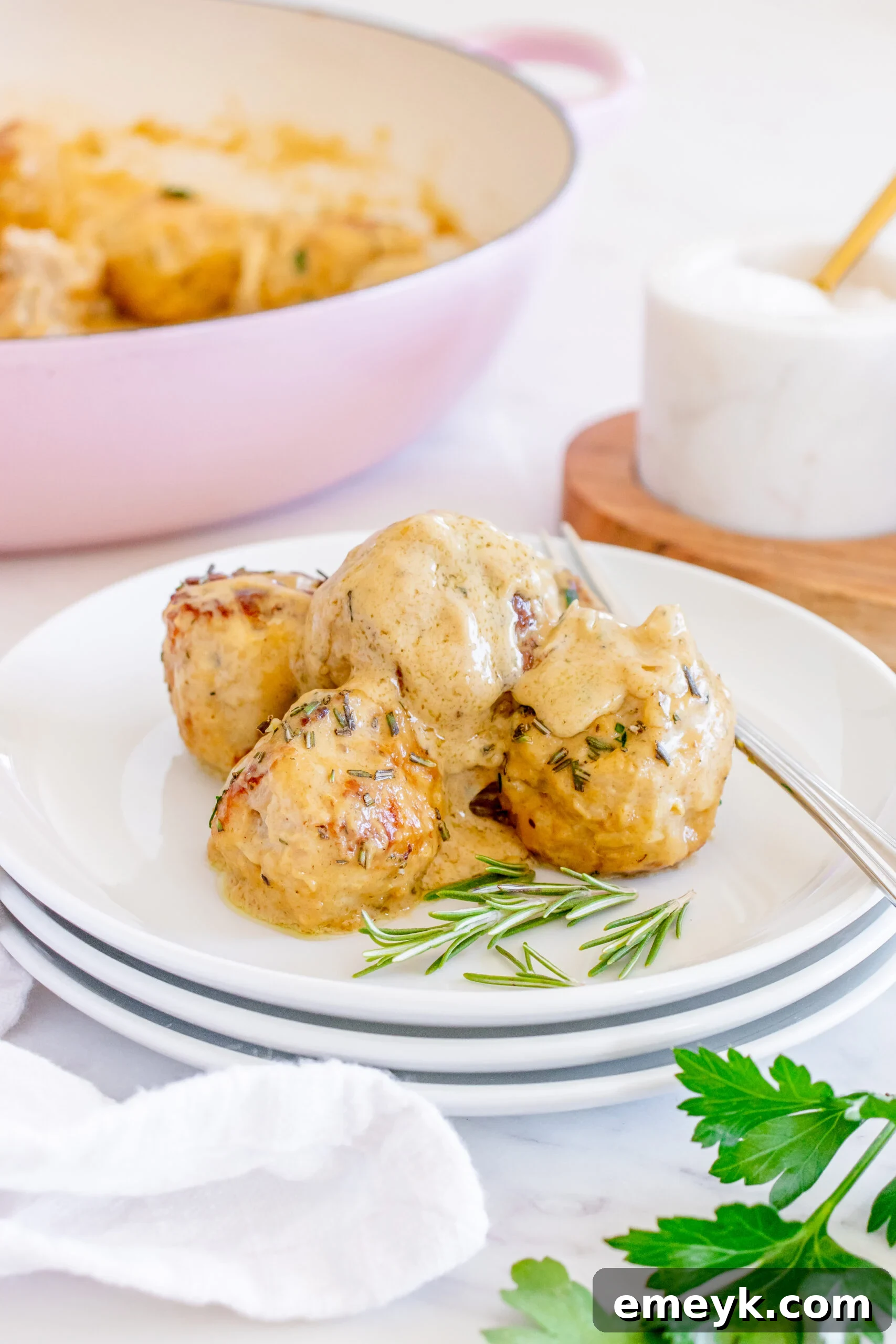 A close-up of a Maple Dijon Turkey Meatball being lifted from a pot with a fork, showing its tender texture and the creamy sauce.