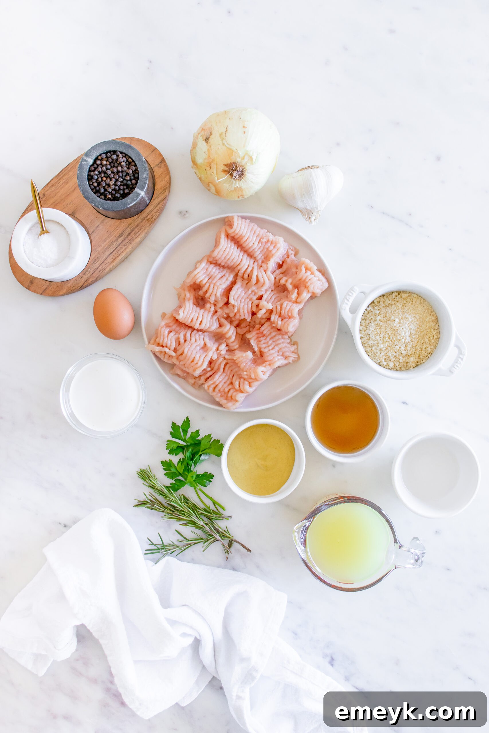 Various ingredients for Maple Dijon Turkey Meatballs laid out on a counter, including ground turkey, panko, onion, garlic, rosemary, and sauce components.