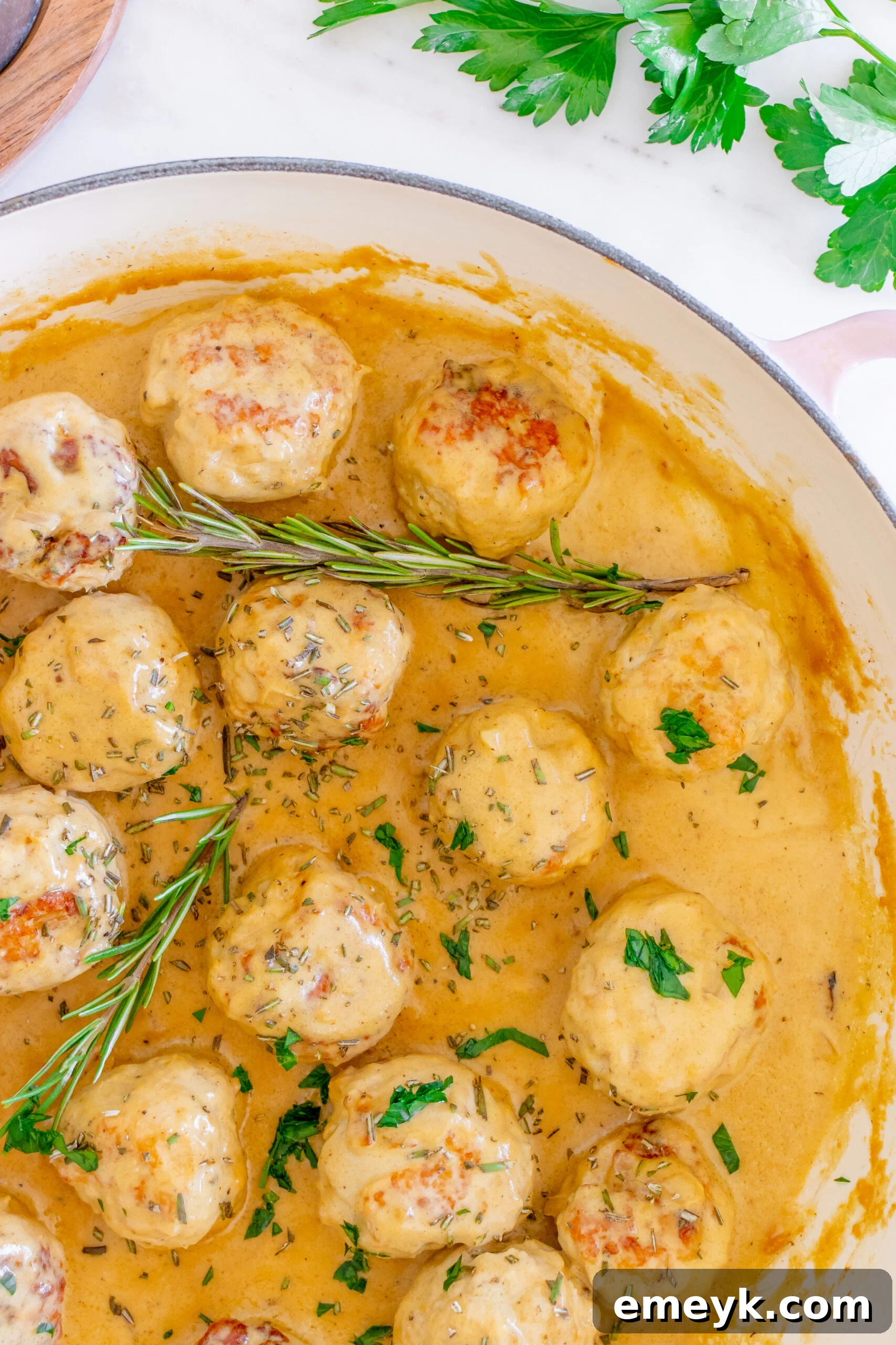 Maple Dijon Turkey Meatballs garnished with fresh rosemary in a pan.