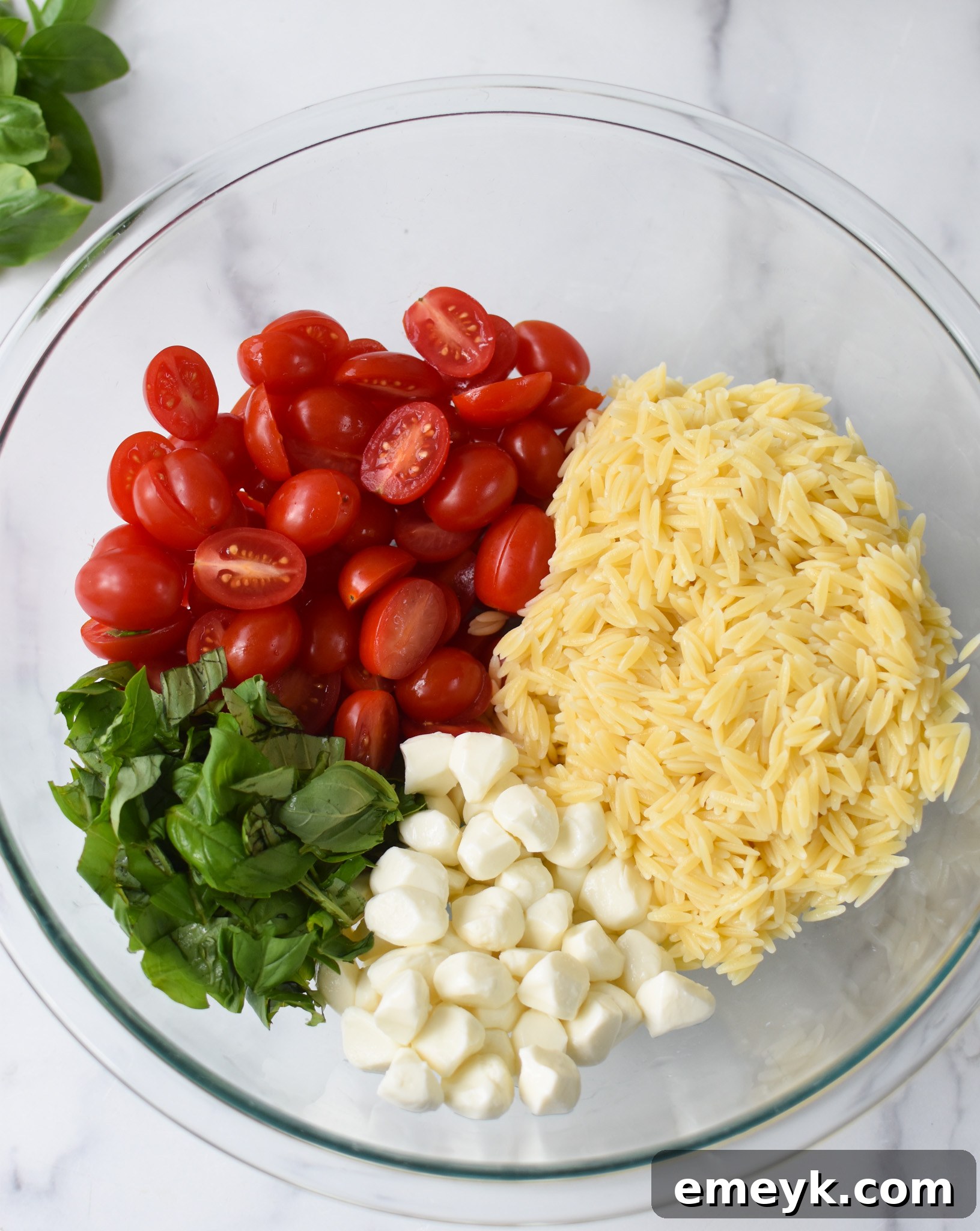 Caprese Orzo Delight 8 Caprese Orzo Pasta Salad ingredients, including cooked orzo, in a large mixing bowl.