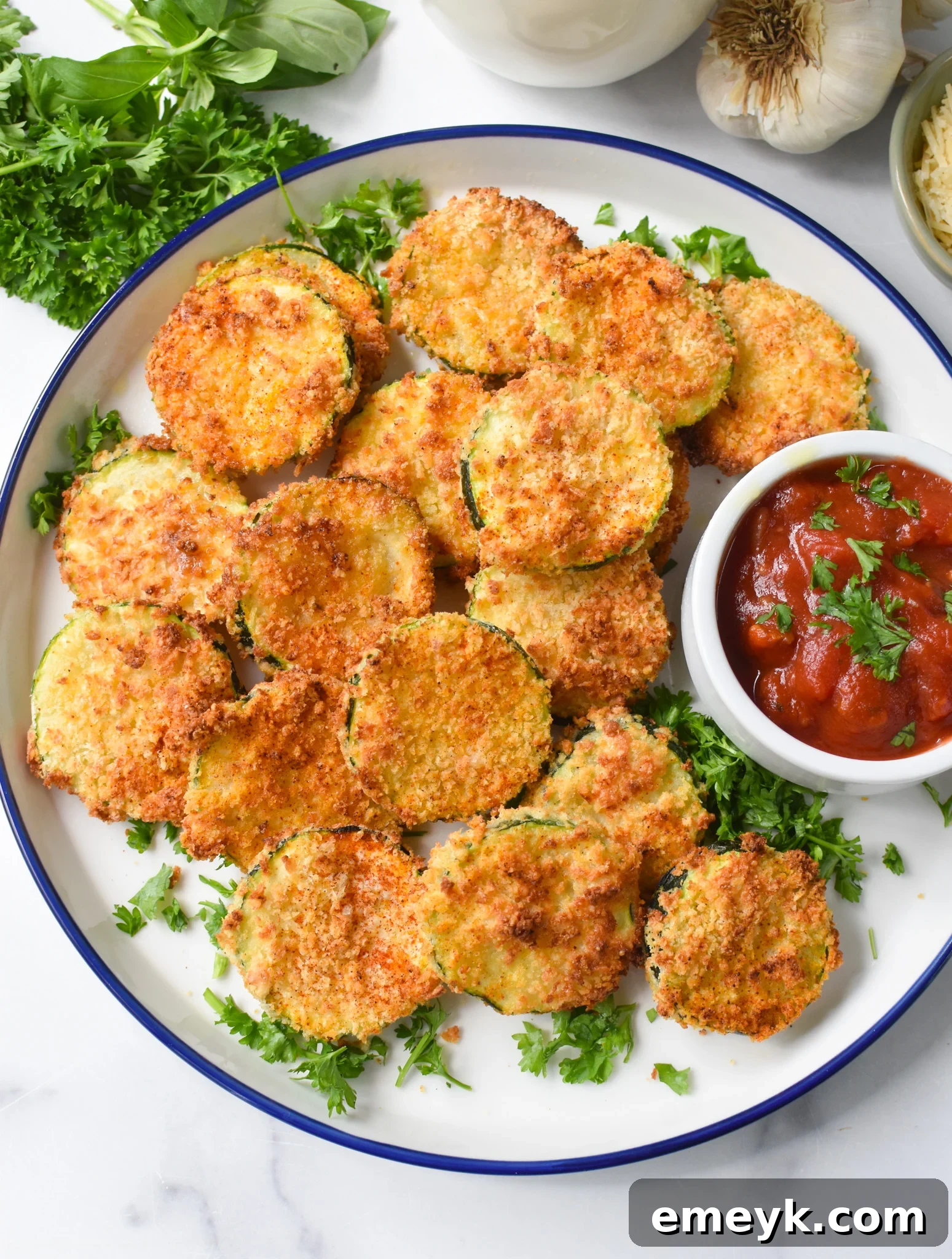 Air Fryer Zucchini Chips served on a rustic wooden board, garnished with fresh parsley and accompanied by a small bowl of marinara sauce.
