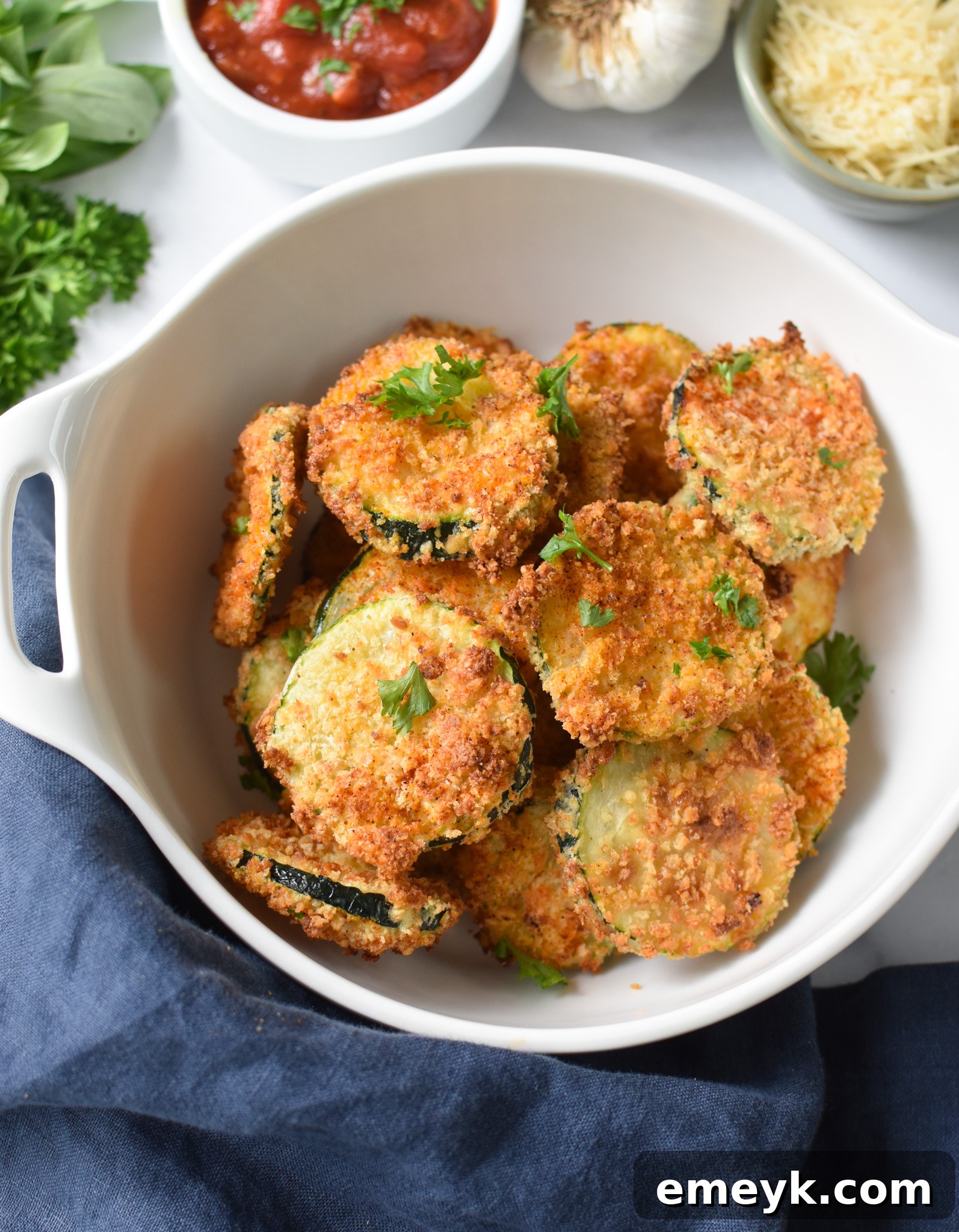 A bowl of freshly cooked Air Fryer Zucchini Chips, with a brand logo subtly placed in the corner, highlighting its homemade appeal.
