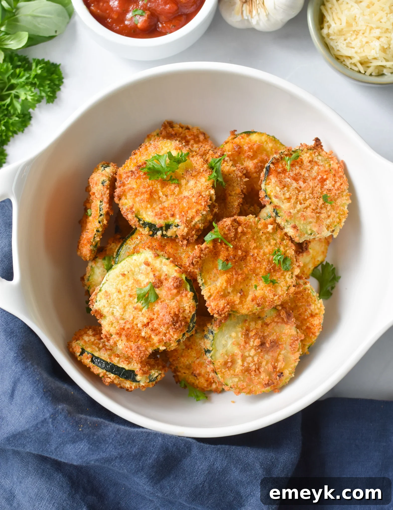 A bowl overflowing with freshly air-fried zucchini chips, showcasing their golden-brown crispness and appealing texture, ready for dipping.