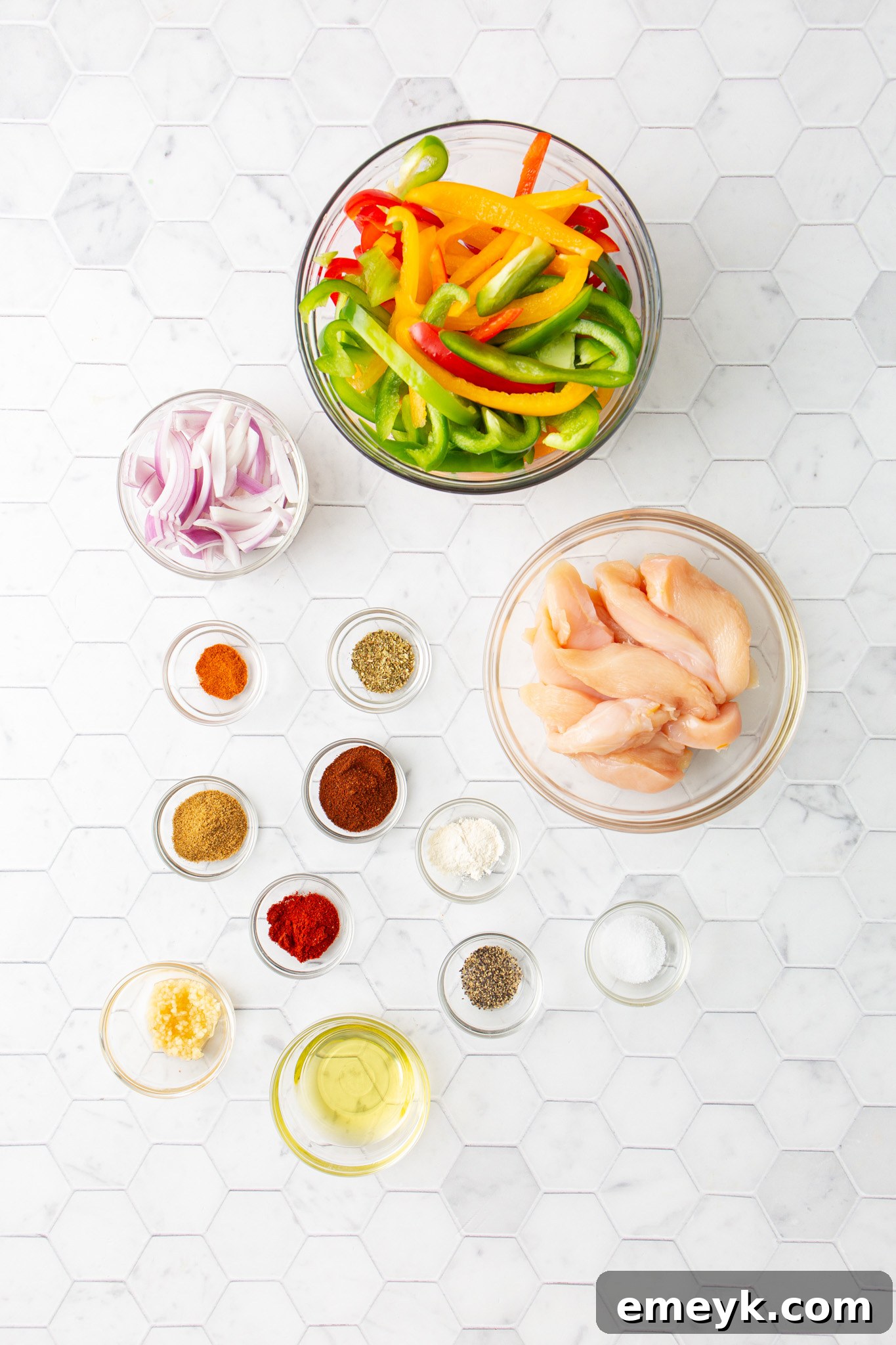 A selection of fresh ingredients including sliced chicken, bell peppers, onions, and spices, ready for Sheet Pan Chicken Fajitas.