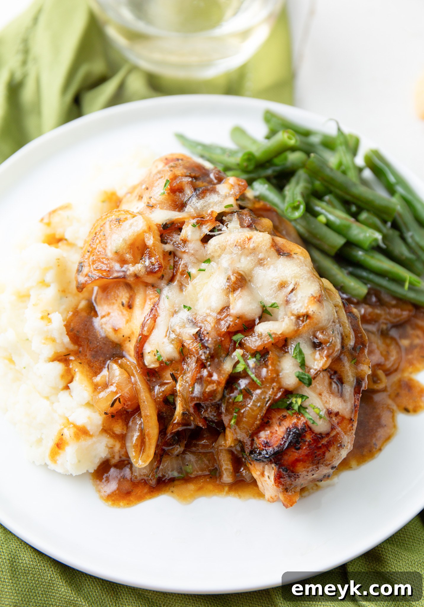 A serving of French Onion Chicken on a white plate, garnished with fresh parsley.