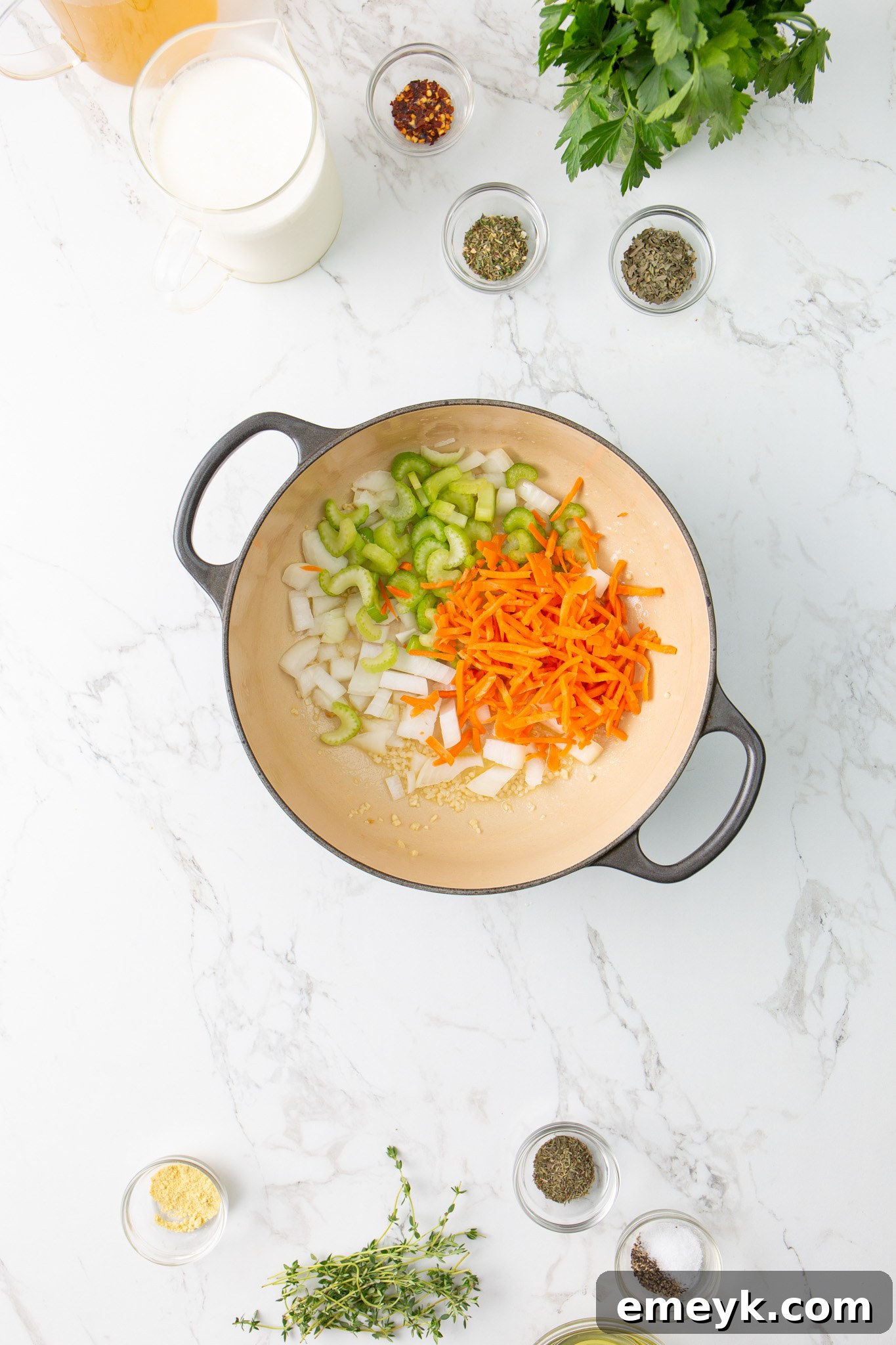 Chopped garlic, onions, celery, and carrots sautéing in butter in a large pot, forming the aromatic base of the soup.