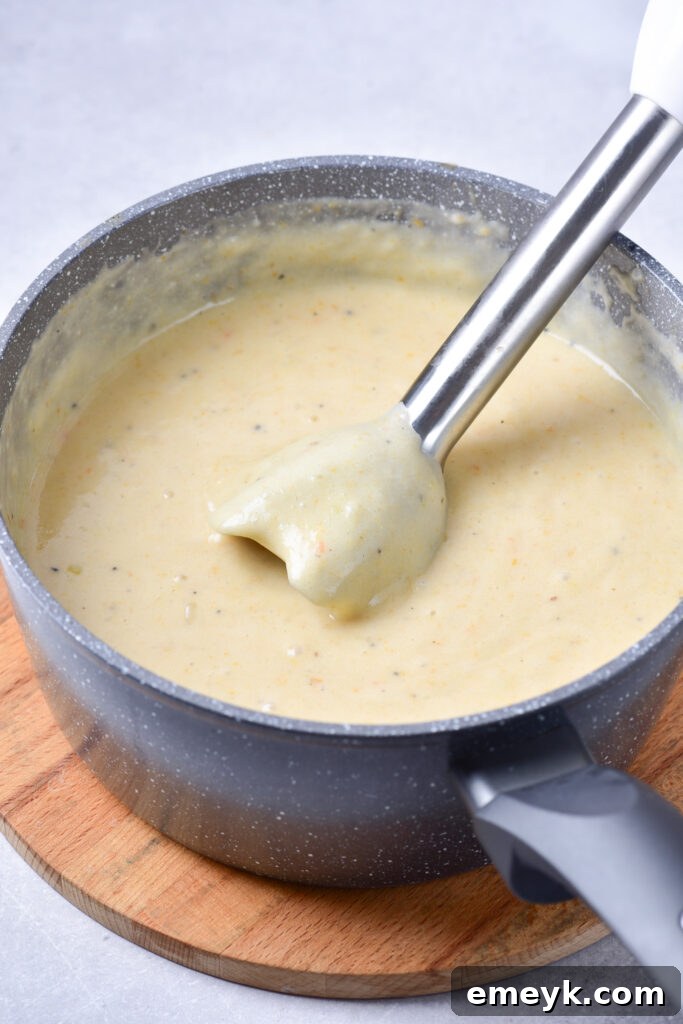 Potato Leek Soup being pureed with an immersion blender in a large pot, showing the final creamy texture.