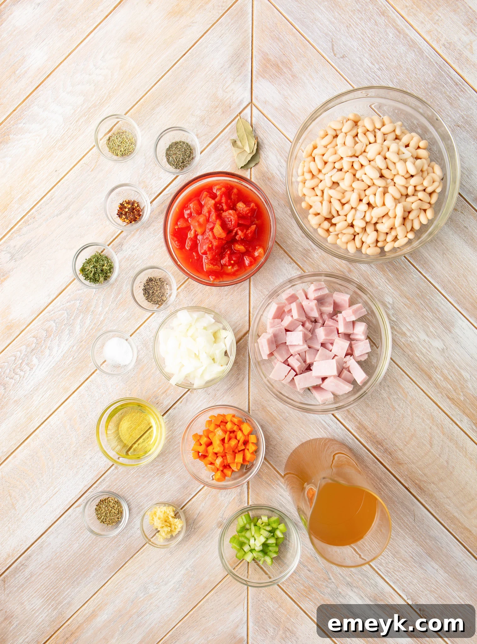 Fresh ingredients laid out for Navy Bean Soup, including navy beans, diced ham, carrots, celery, onion, and various dried herbs.