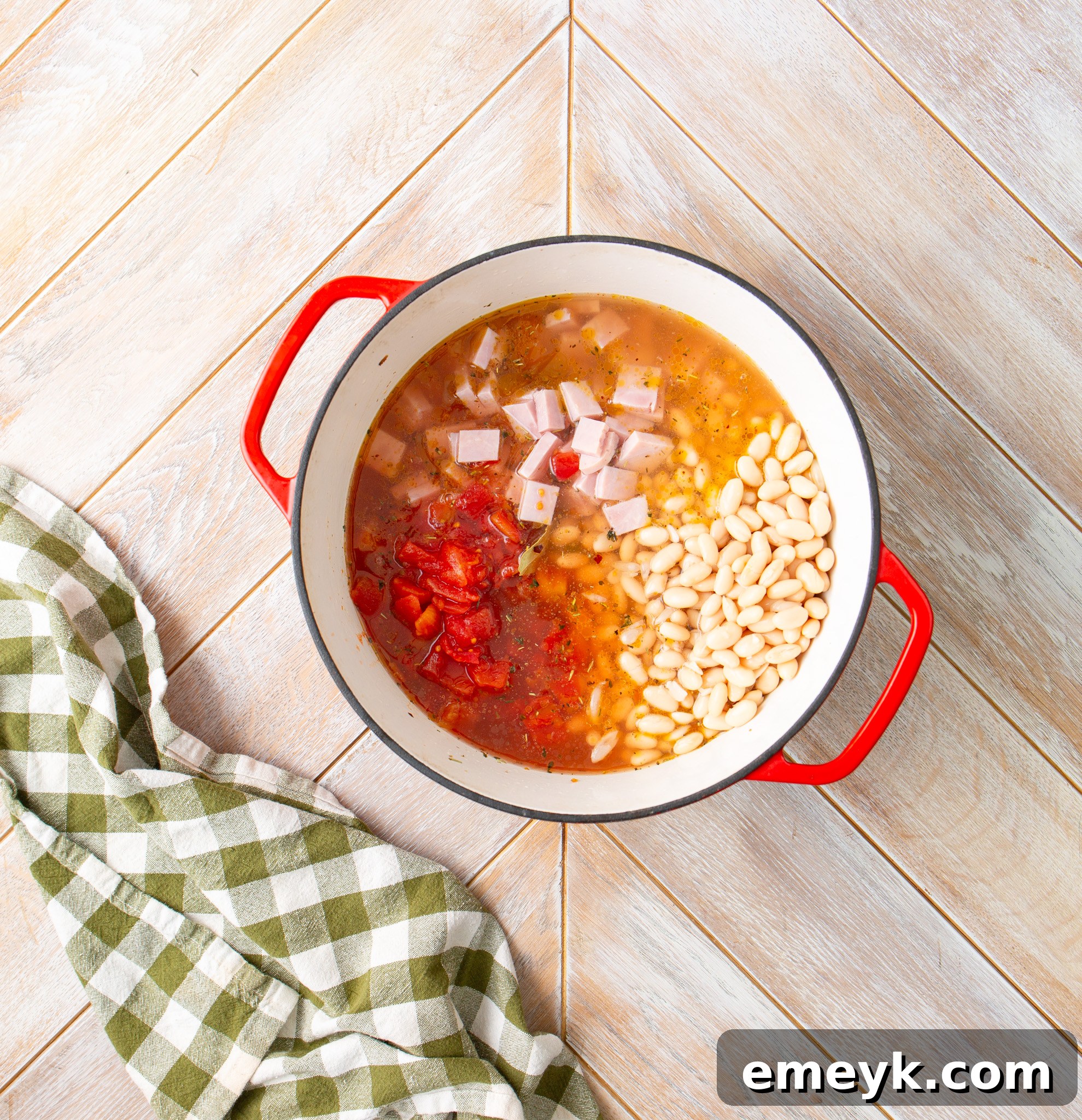 Diced tomatoes, ham, and navy beans added to the pot with broth, ready to simmer for Navy Bean Soup.