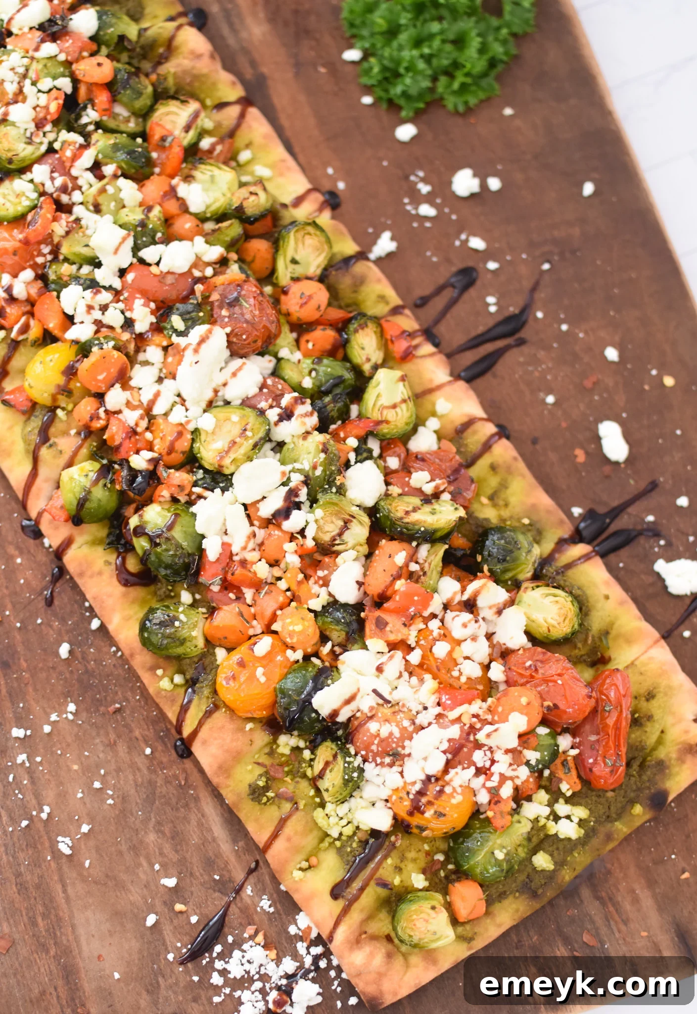 Delicious Roasted Vegetable Goat Cheese Flatbread Pizza on a rustic cutting board, ready to be served.