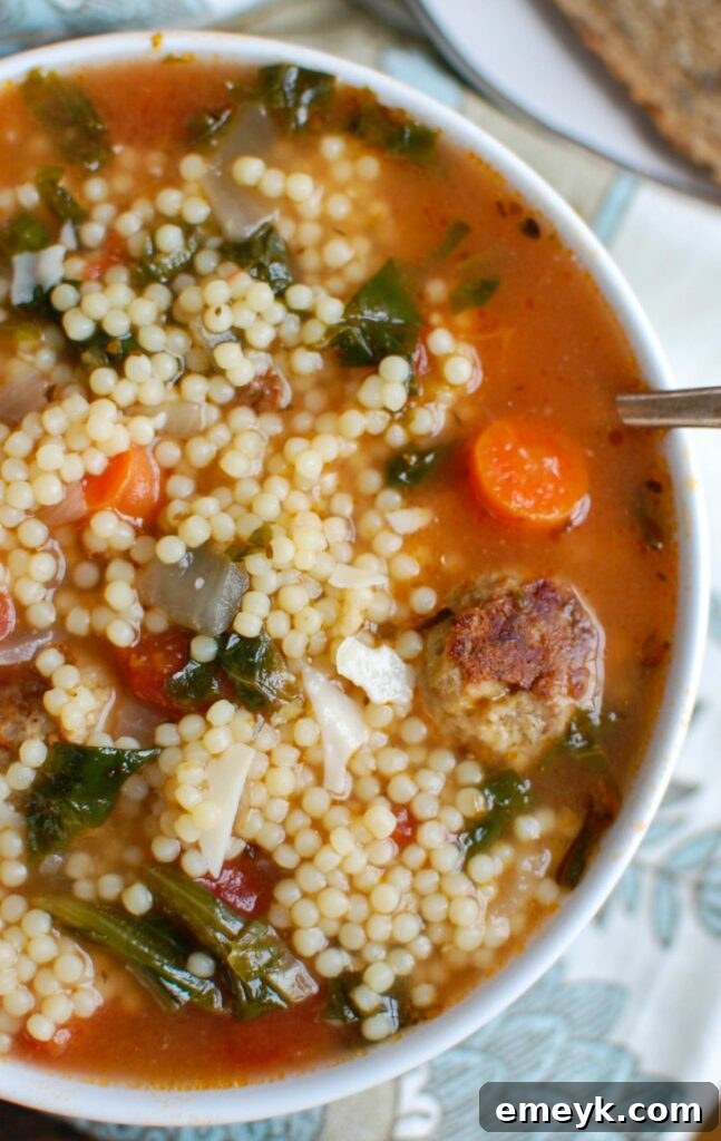 A steaming bowl of healthy Italian Wedding Soup with turkey meatballs, escarole, and small pasta, garnished with fresh parsley.