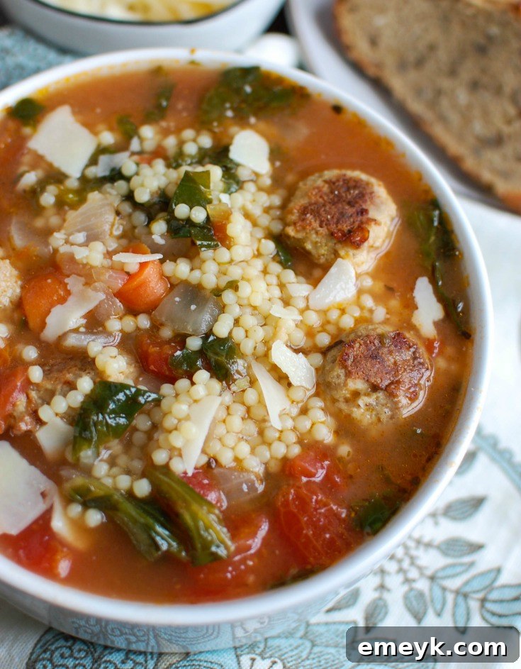 Turkey meatballs being gently dropped into the simmering Italian Wedding Soup with vegetables and broth.