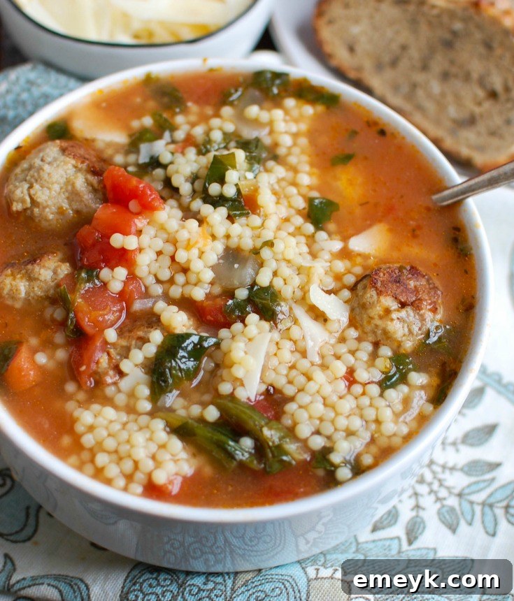 A beautifully presented bowl of Italian Wedding Soup, ready to be enjoyed with a sprinkle of Parmesan cheese.
