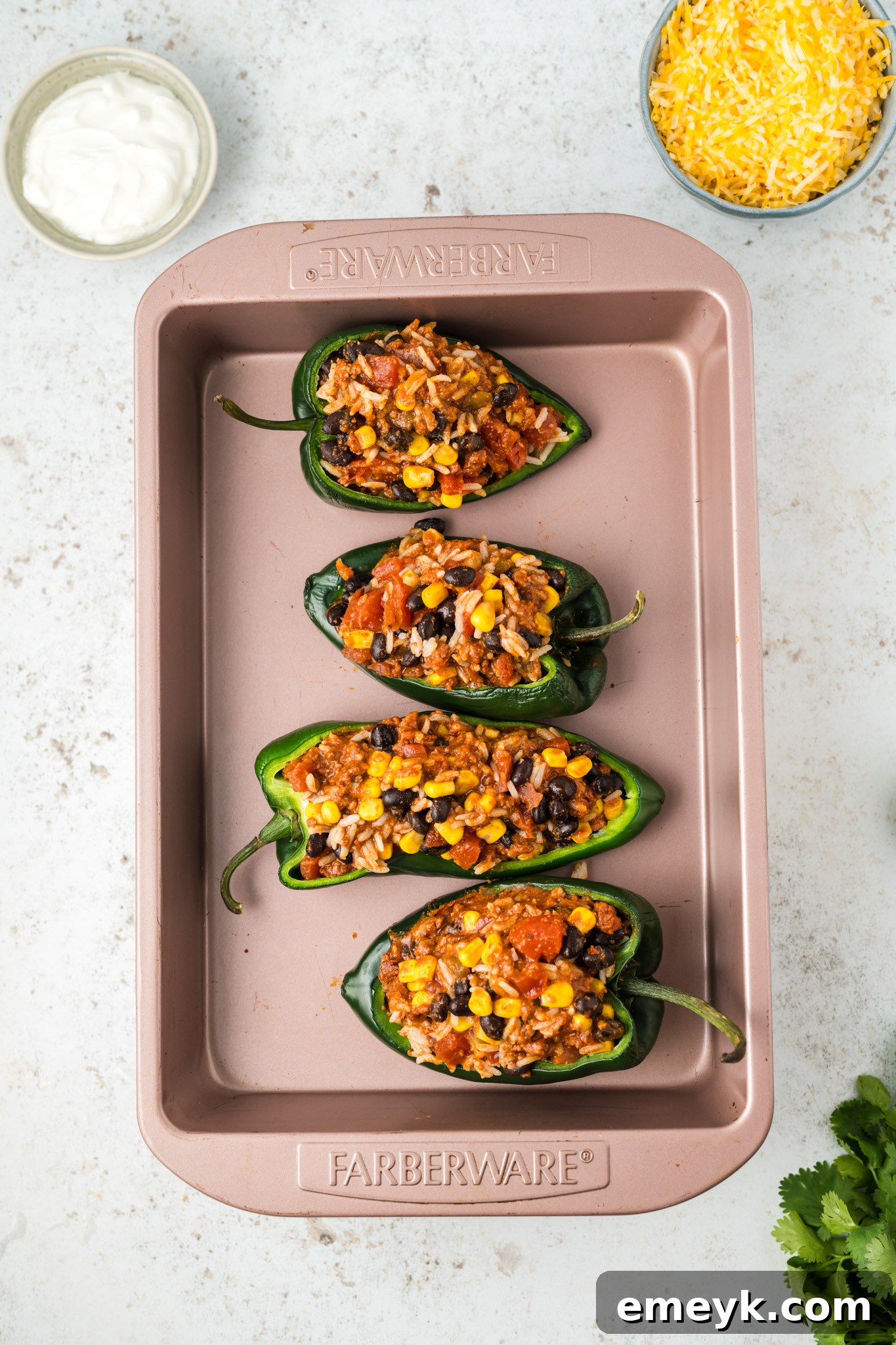 Raw poblano pepper halves generously filled with the savory chorizo, rice, and bean mixture, meticulously arranged in a baking dish before adding the cheese topping and baking.