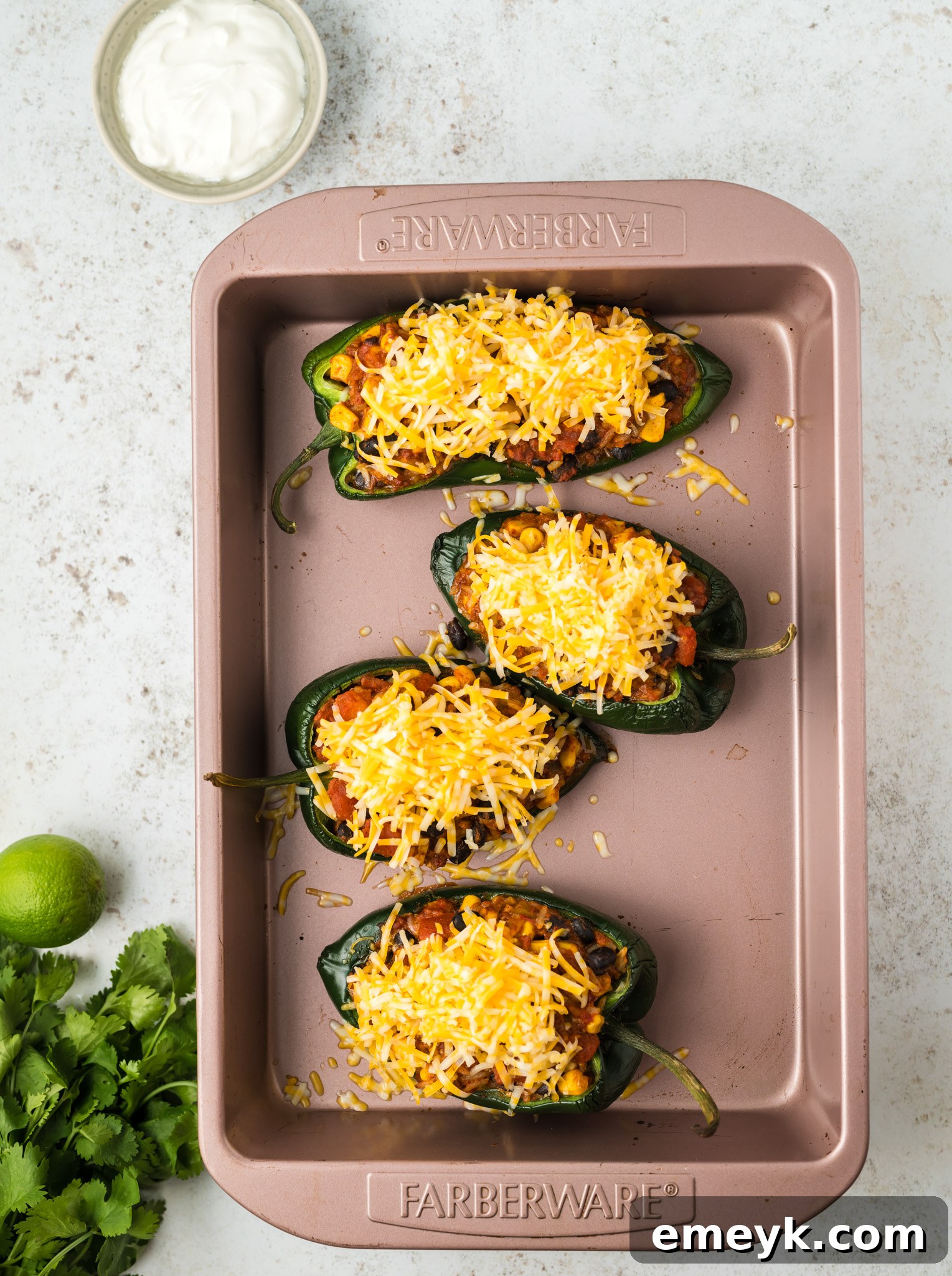 Close-up view of Stuffed Poblano Peppers beautifully topped with a generous layer of shredded Colby Jack cheese, melting perfectly and bubbling in the oven to a golden perfection.