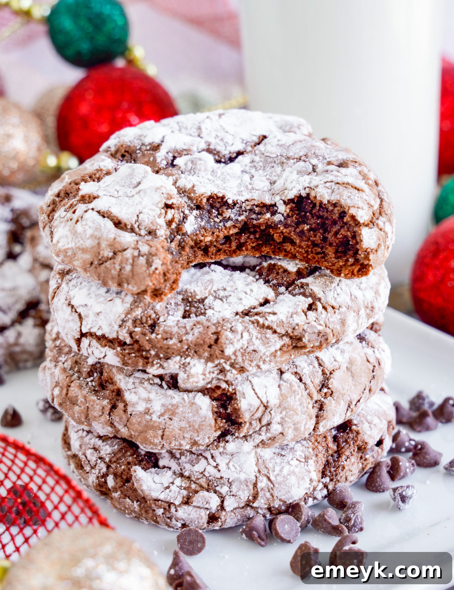 A chocolate crinkle cookie with a bite taken out, showing its soft, fudgy interior and melted chocolate chips.
