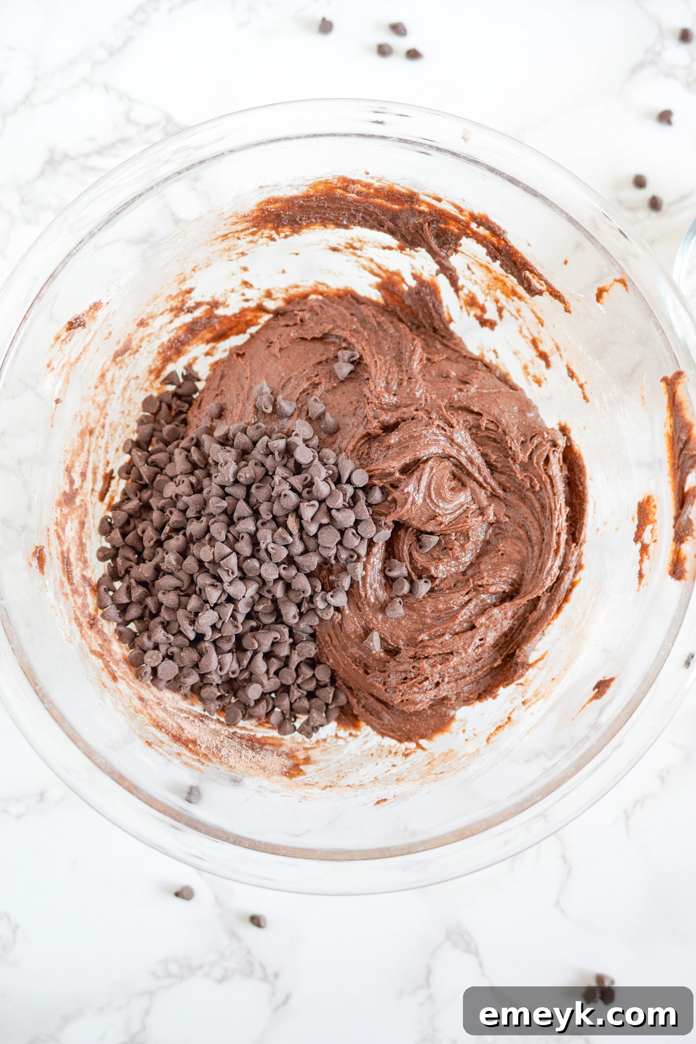 Miniature chocolate chips being stirred into the chocolate crinkle cookie dough.