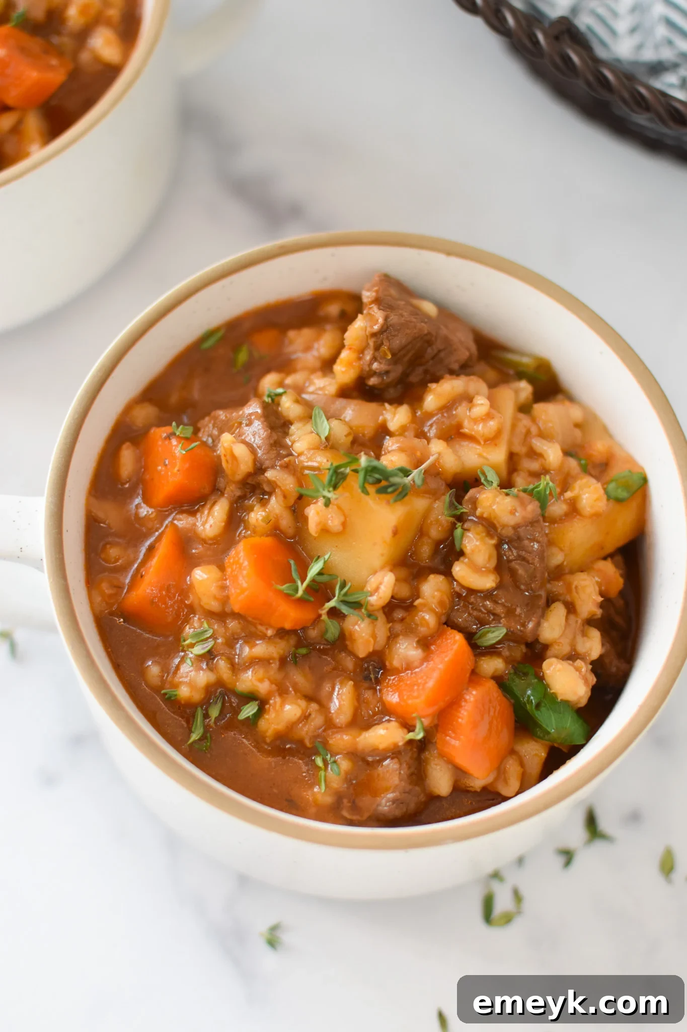 A steaming bowl of Slow Cooker Beef Barley Soup, garnished with fresh herbs, ready to be enjoyed.