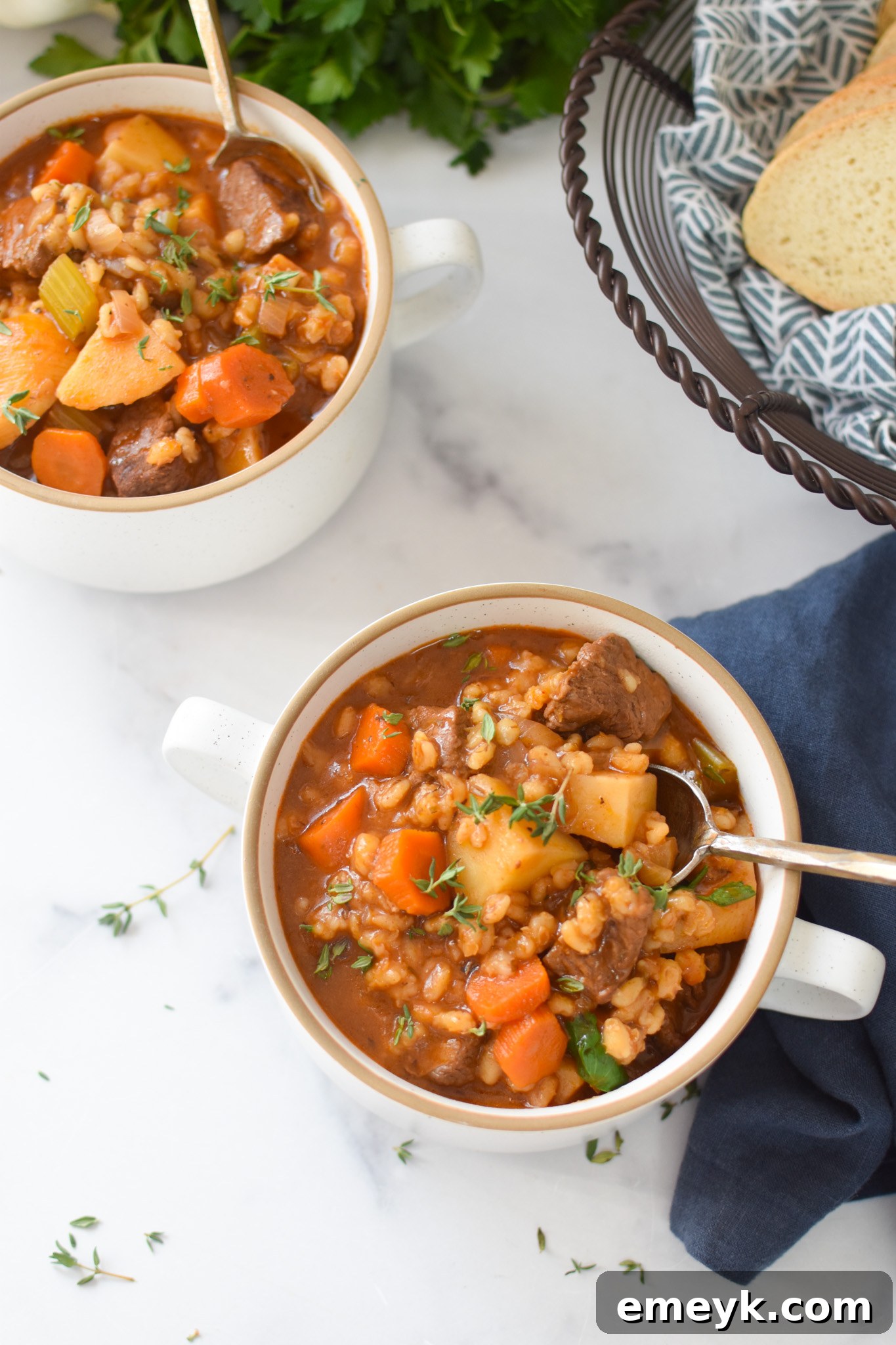 Close-up of Slow Cooker Beef Barley Soup in a white bowl with a spoon, showing the tender beef and plump barley.