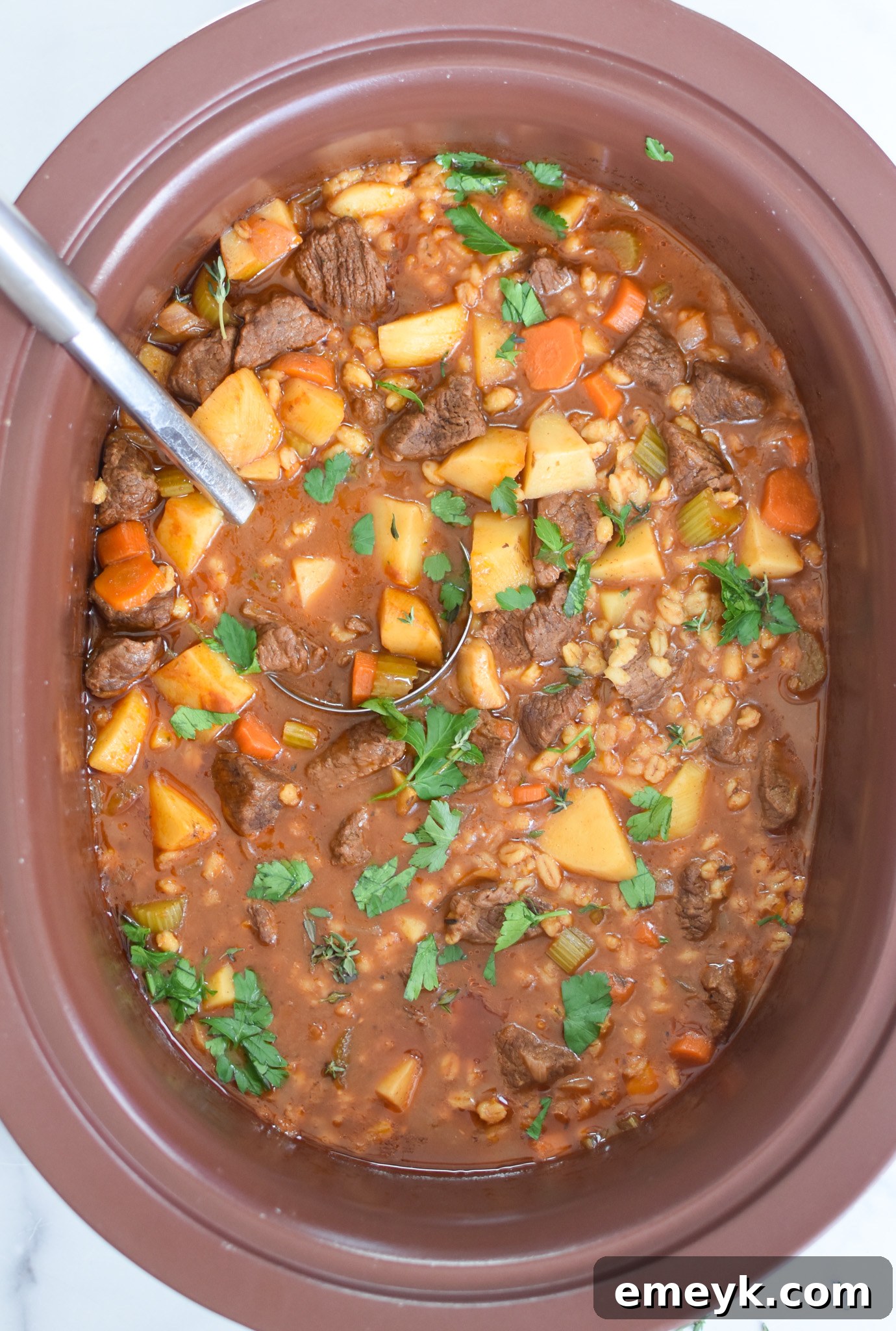 Cooked Slow Cooker Beef Barley Soup bubbling gently in the crockpot, ready to be served.