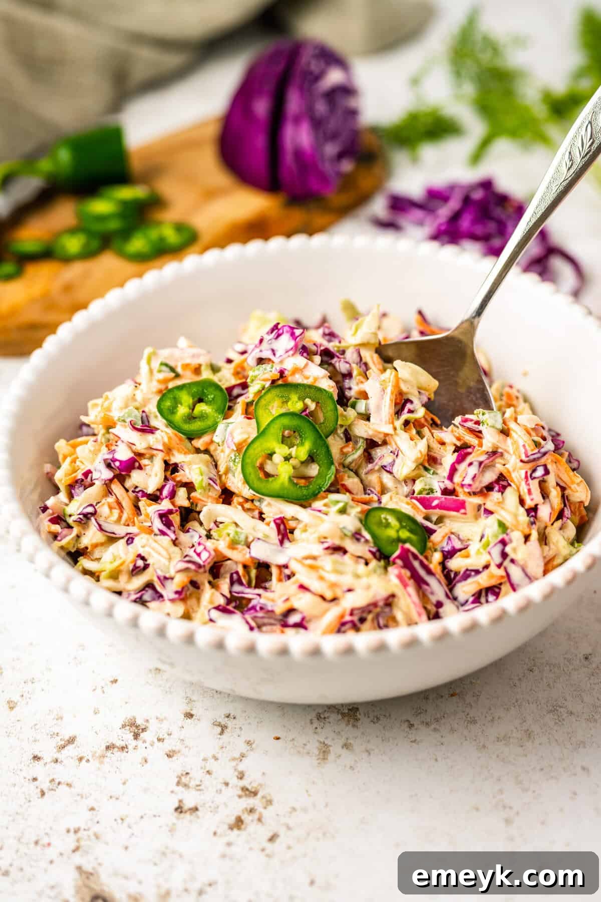 Kickin Jalapeno Coleslaw 2 Jalapeño Coleslaw Recipe in a white bowl with a fork, showcasing its vibrant colors and creamy texture.
