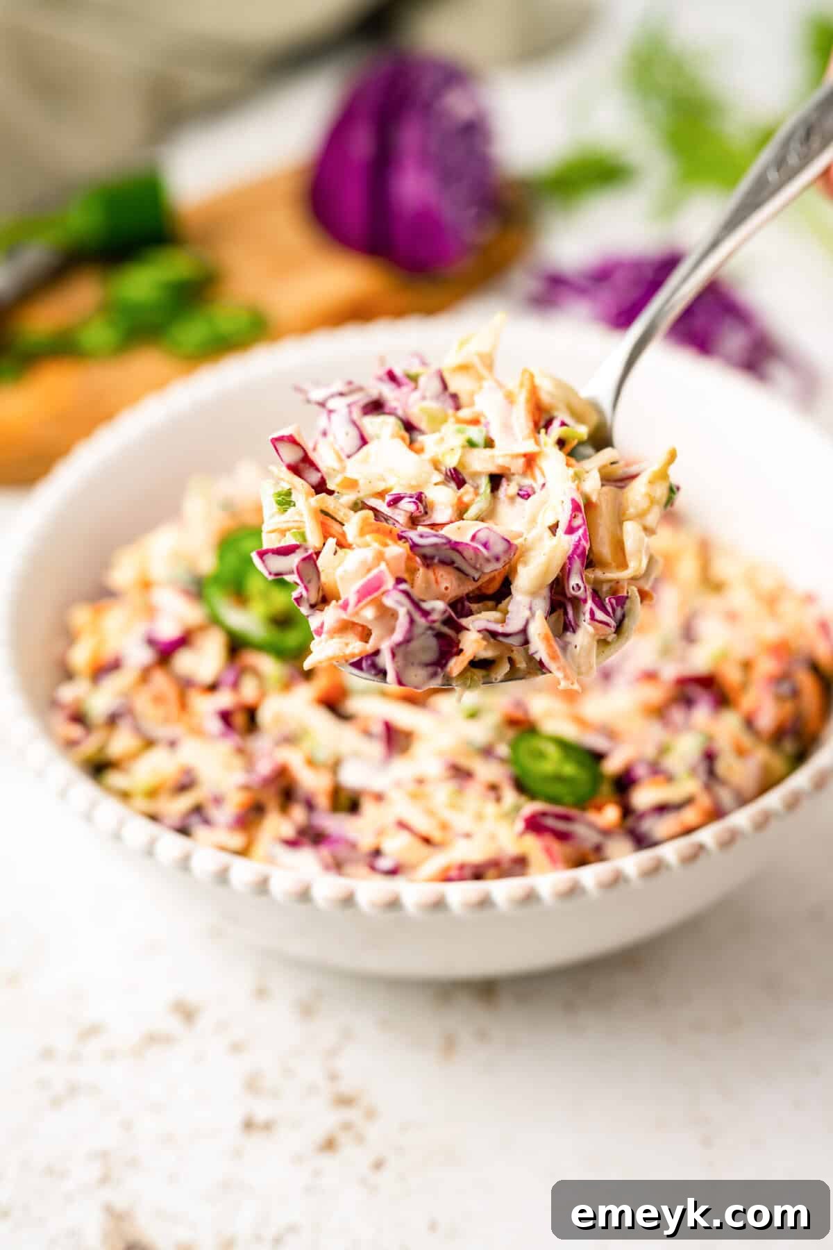 Kickin Jalapeno Coleslaw 7 A fork taking a scoop of the freshly made Jalapeño Coleslaw from a bowl, highlighting its readiness to serve.