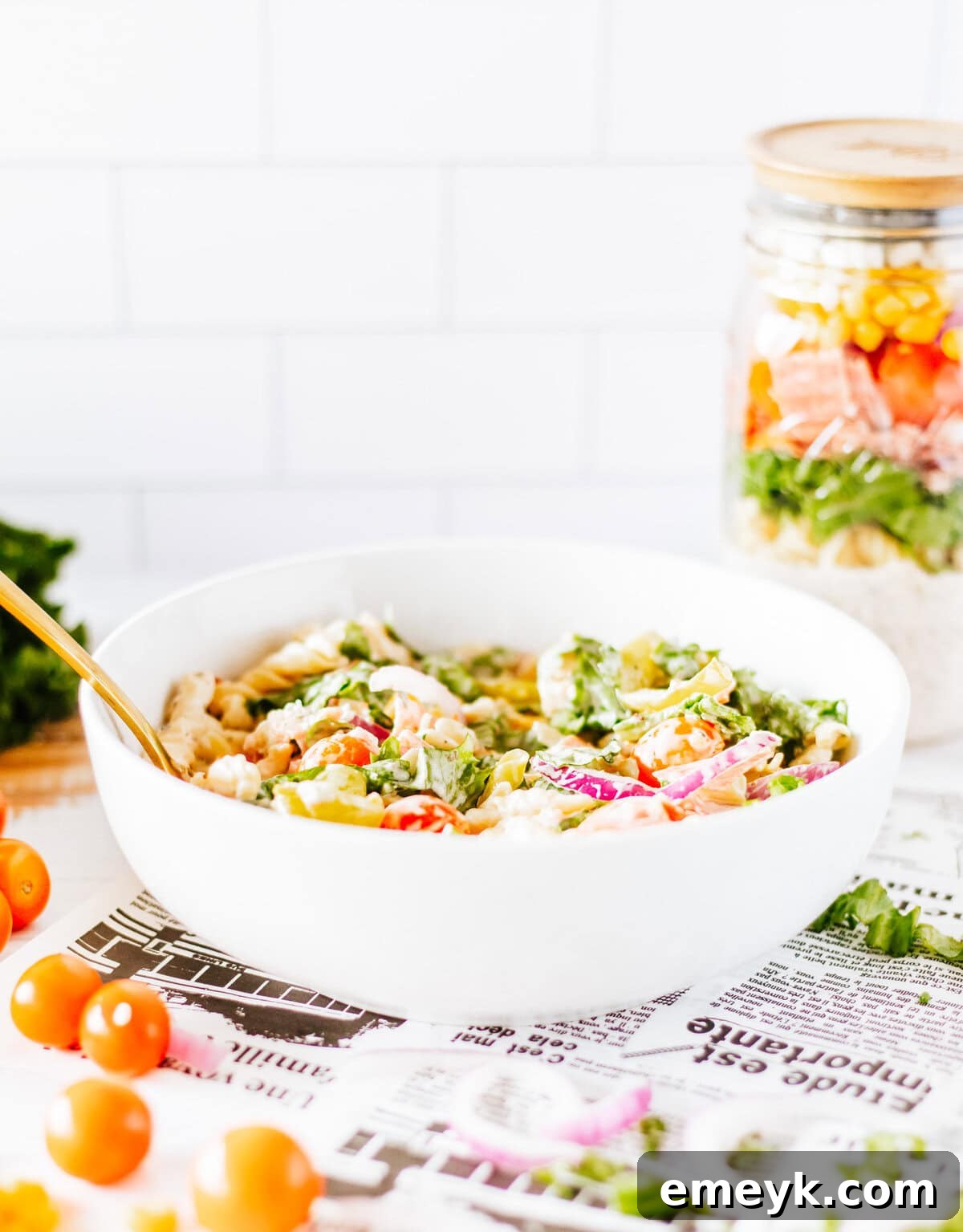 Italian Pasta Mason Jar Salad poured into a bowl and ready to be mixed and eaten, showcasing all the delicious, fresh ingredients.