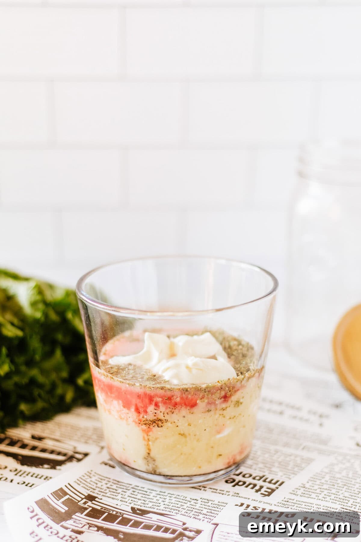 A mason jar with only the creamy Italian dressing poured into the bottom, ready for the next layers of salad ingredients.